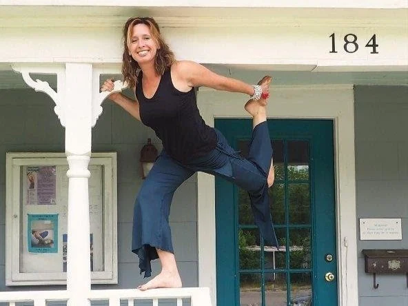 lexie balancing on wooden porch railing, holding foot