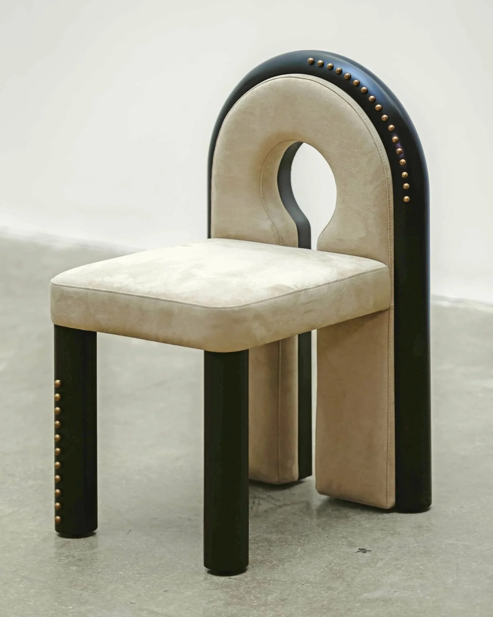 Beige velvet chair with sculptural black arched backrest and brass studs designed by Eva Szumilas Studio Beirut