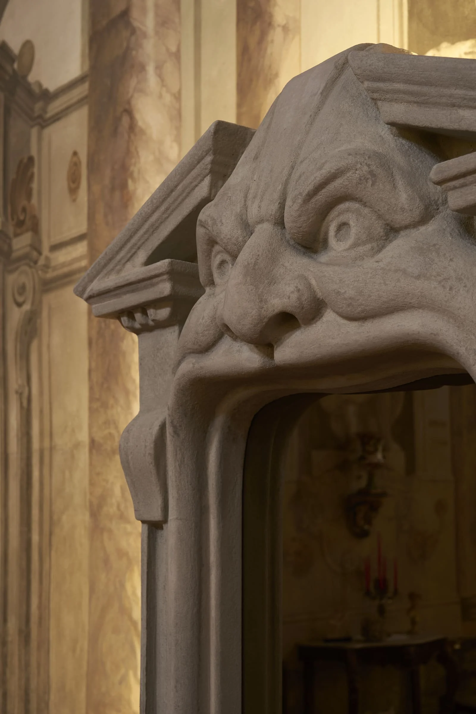 Close-up of the carved grotesque face and pediment detailing on the Chimera mirror by Francesco Maria Messina