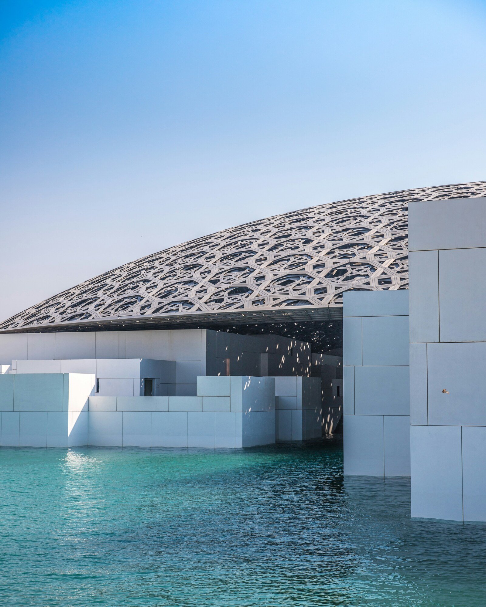 Louvre Abu Dhabi designed by Jean Nouvel with its geometric dome, water and white museum buildings