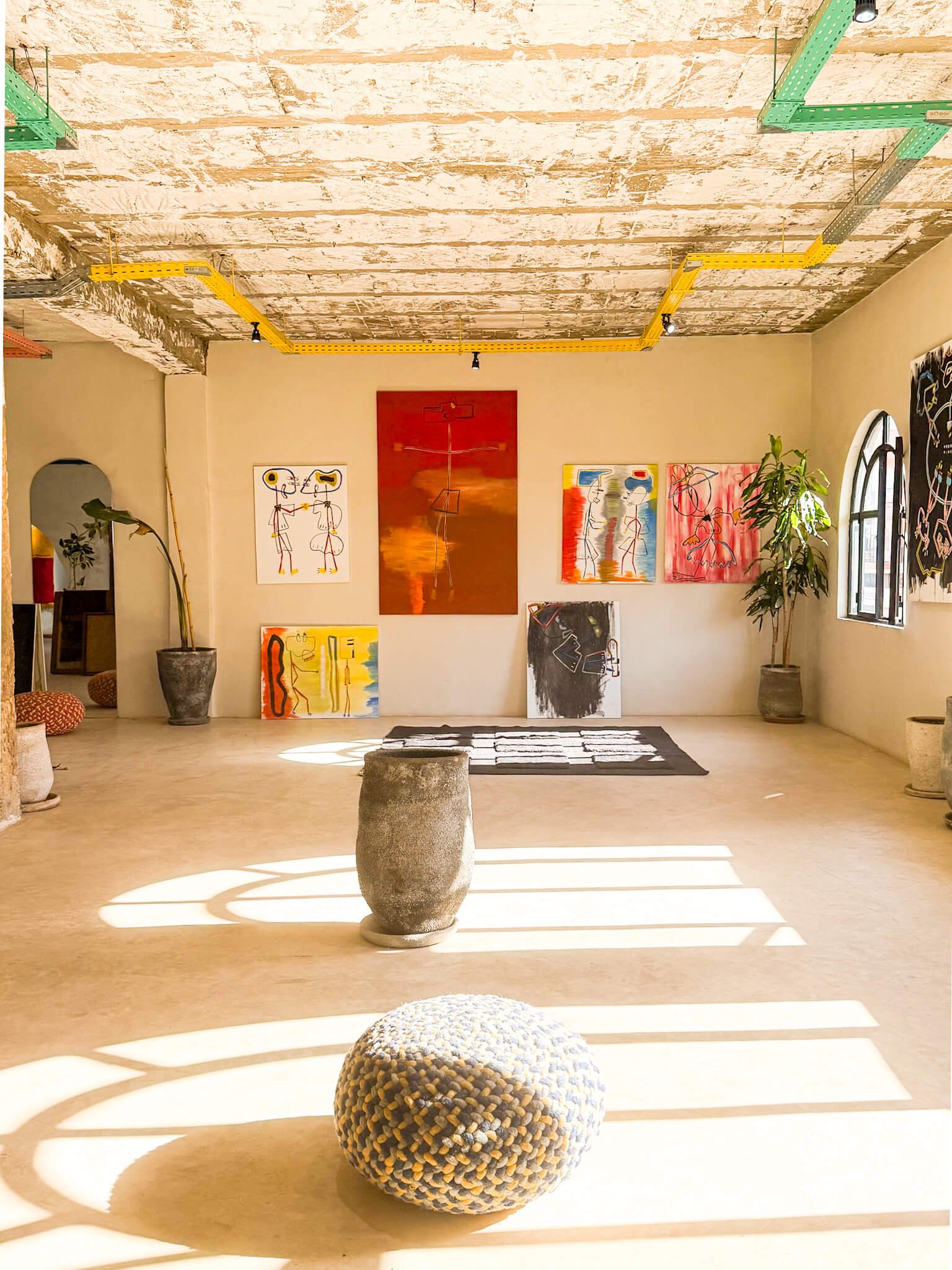 Studio shot showing rugs, sketches and sculptural pieces.