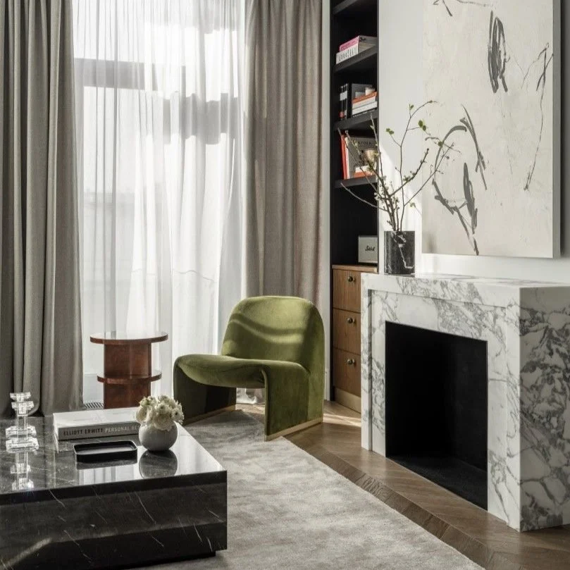 Elegant living room with a green chair, marble fireplace, and minimalist decor.
