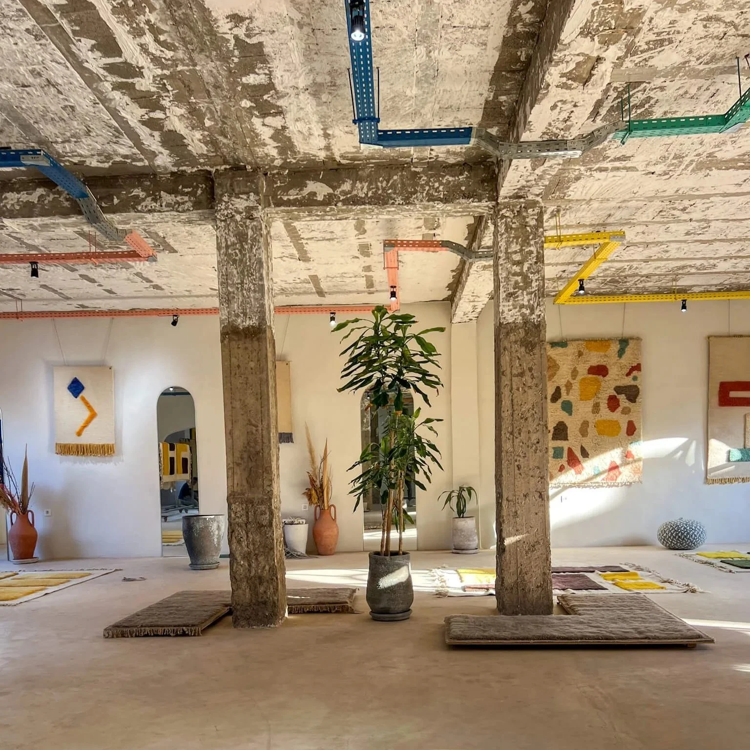 Studio shot showing rugs, sketches and sculptural pieces.