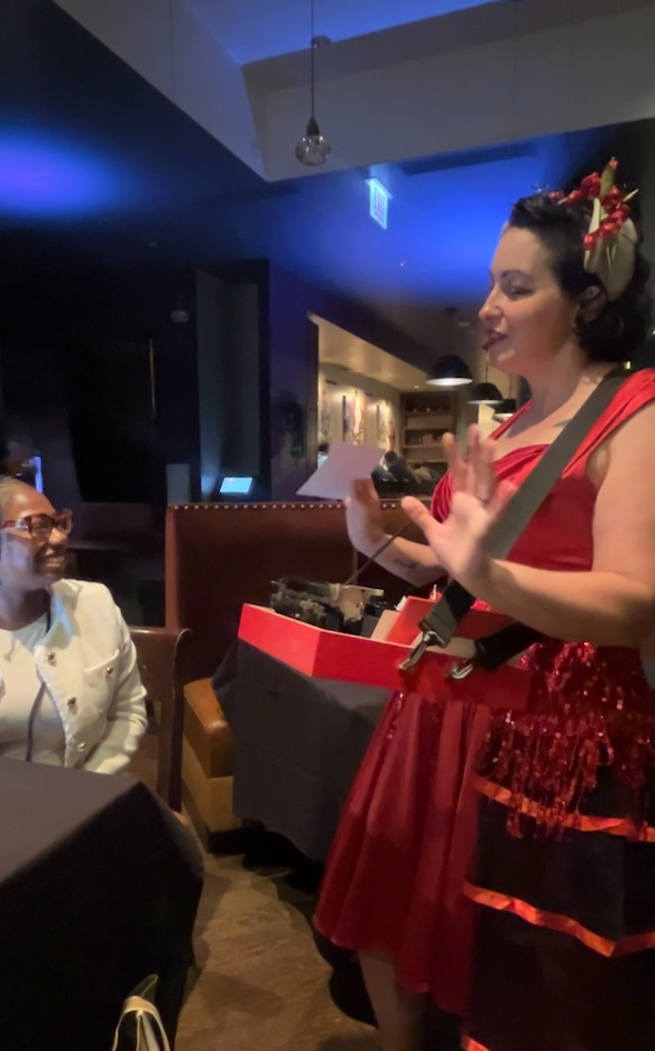 a woman in a red dress performs strolling typewriter poetry at a party in chicago