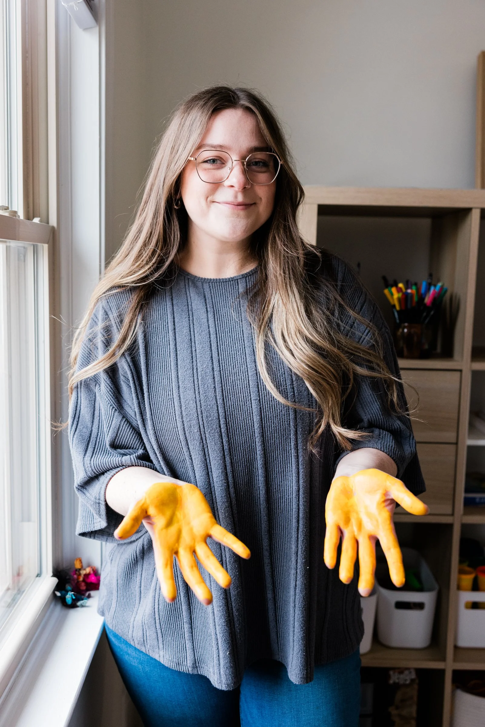 DBT therapy near Herndon. Parent coaching near me. Art and play therapy near me. Therapy for anxiety. A person with yellow paint on their hands holds them out to the camera.