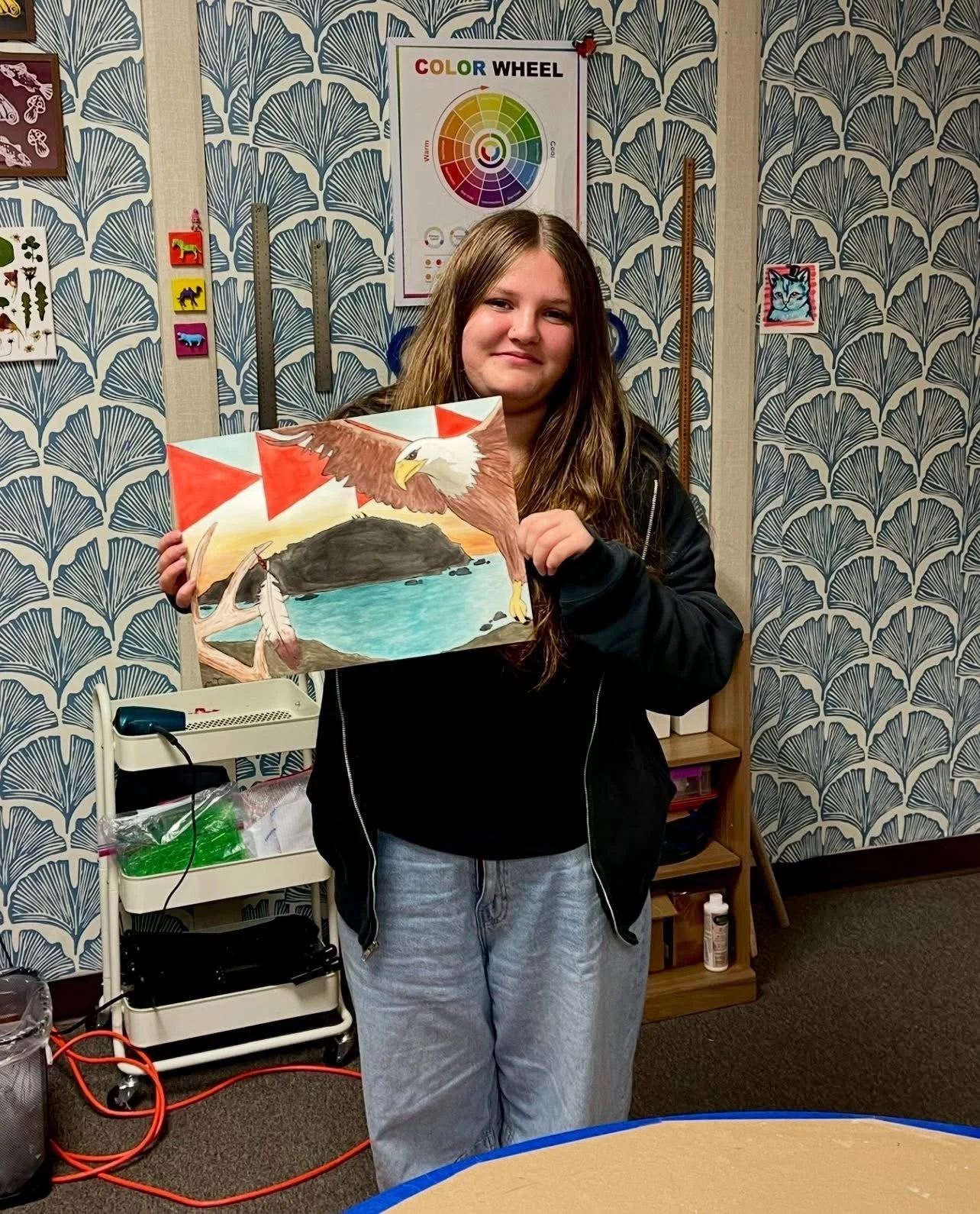 Local youth artist poses with art created during a DiRT & Glitter visual arts class with Jessica Cherry in Del Norte County, CA