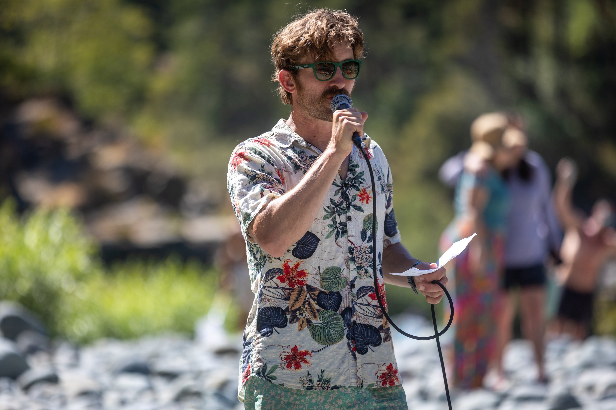Photo of DiRT & Glitter's Adventure Lead, Adam Spencer of Redwood Rides, giving the community a safety talk before getting on the Smith River for Breathing Bridges 2025 in Del Norte County