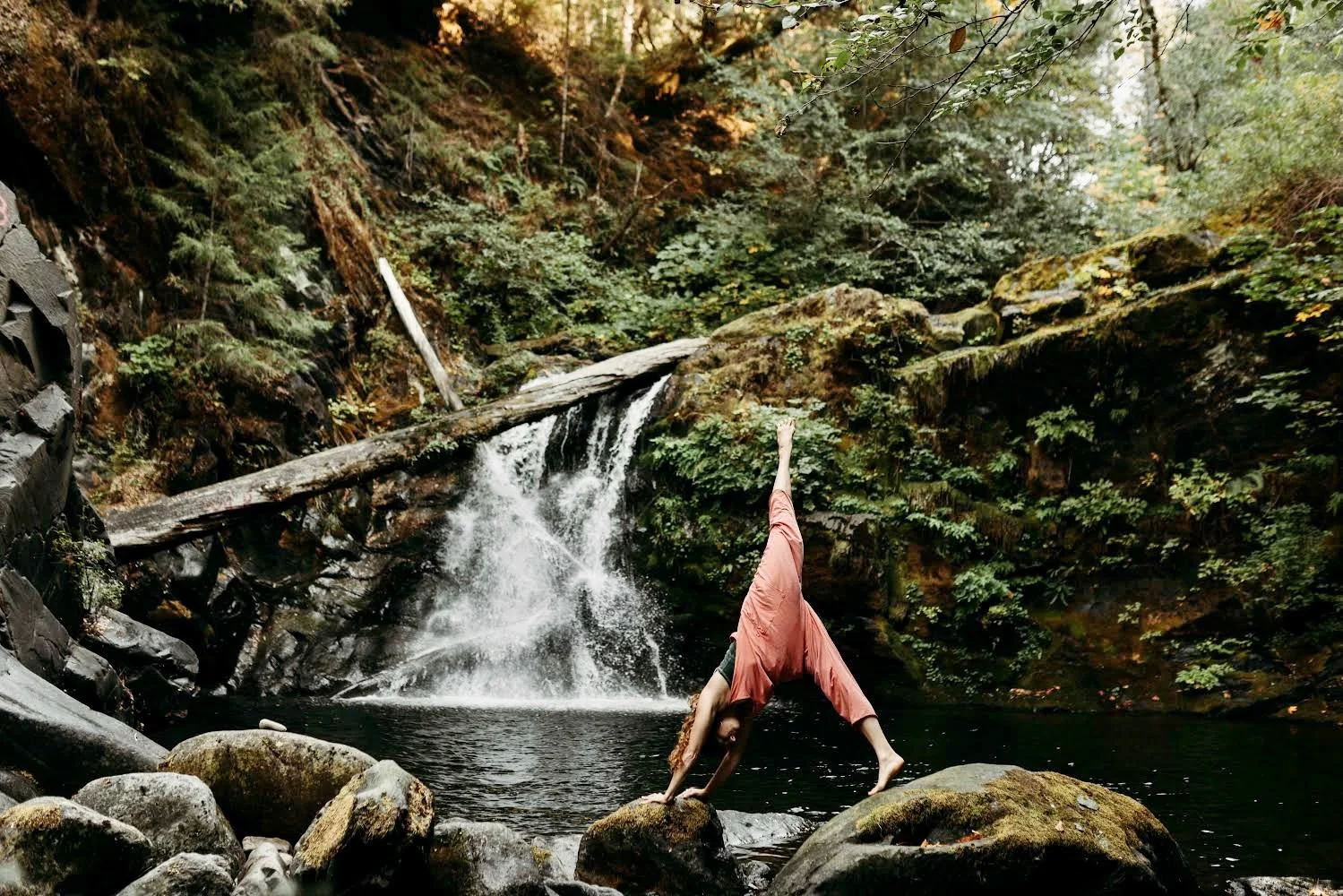 A photo of DiRT & Glitter founder Lauren Godla doing a yoga stretch next to a waterfall in Del Norte County, CA