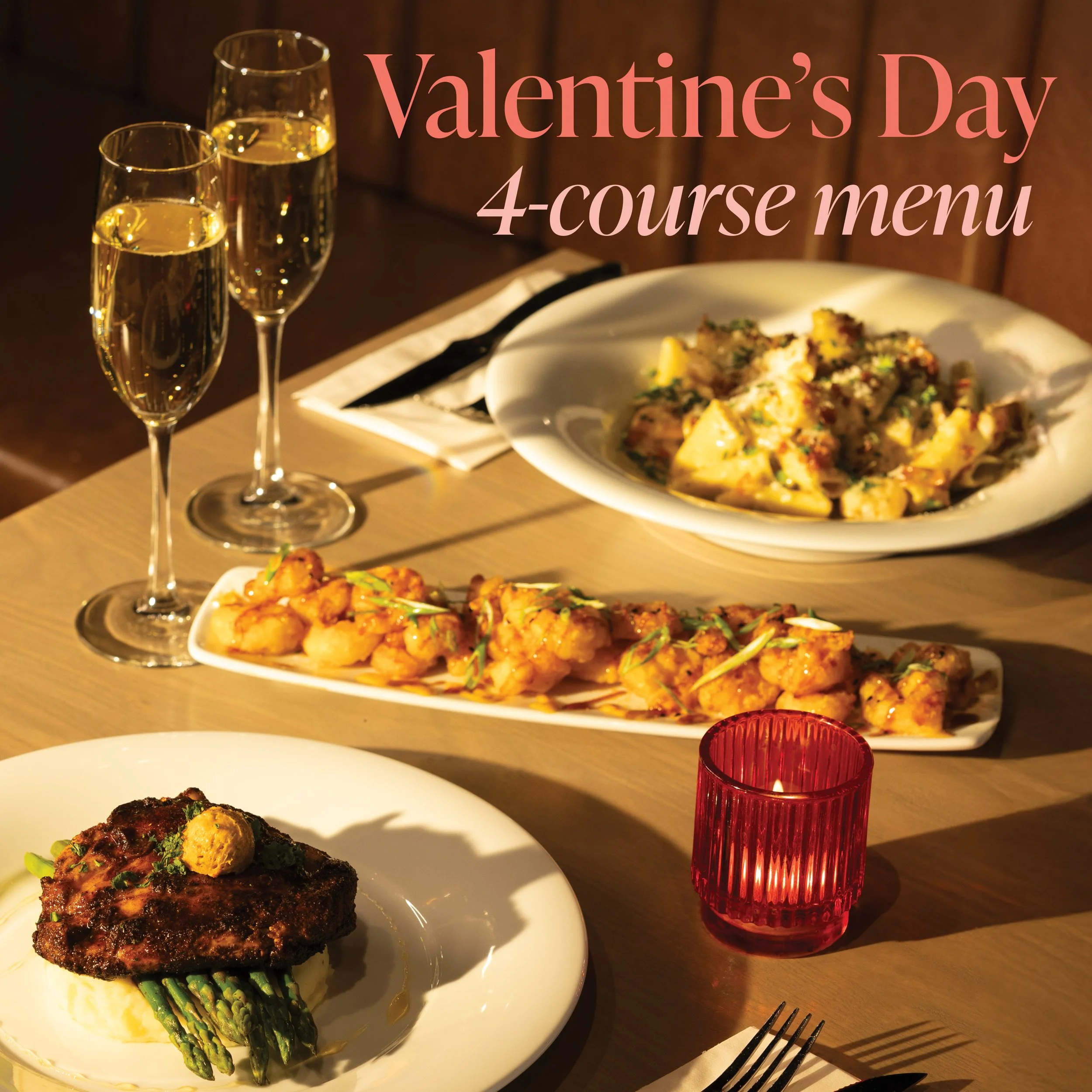 Table with a white plate of grilled meat with asparagus, a bowl of baked pasta, two glasses of white wine, and a red candle holder.