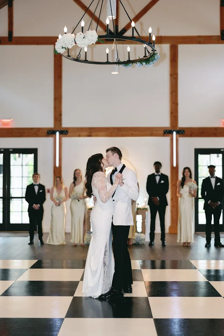 Bride and groom celebrating at Celebration Grove wedding venue in Vero Beach — testimonial from a Google review. Groom is wearing a black and white tuxedo dancing with his bride on a black and white checkered dancefloor in the reception hall.