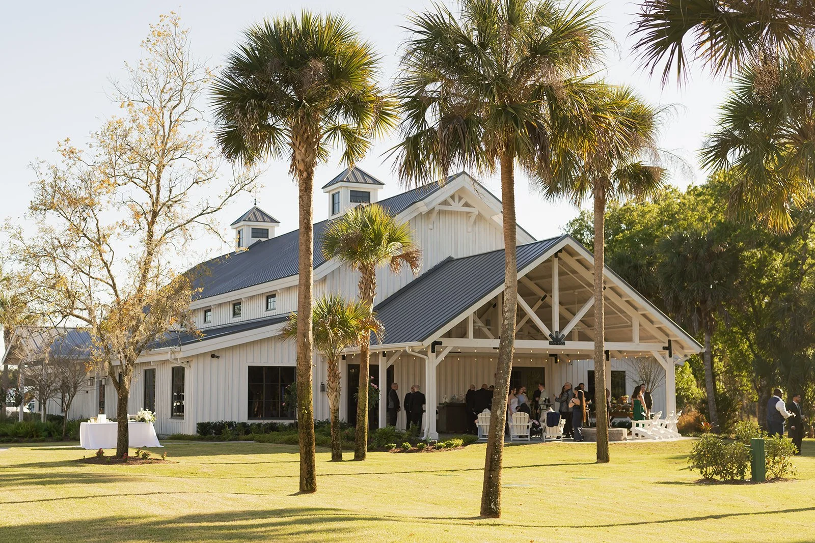Covered veranda at Celebration Grove in Vero Beach with bar-top tables, cooling fans, and garden lights for cocktail hours and open-air mingling.
