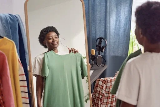 A woman holding up a t-shirt.