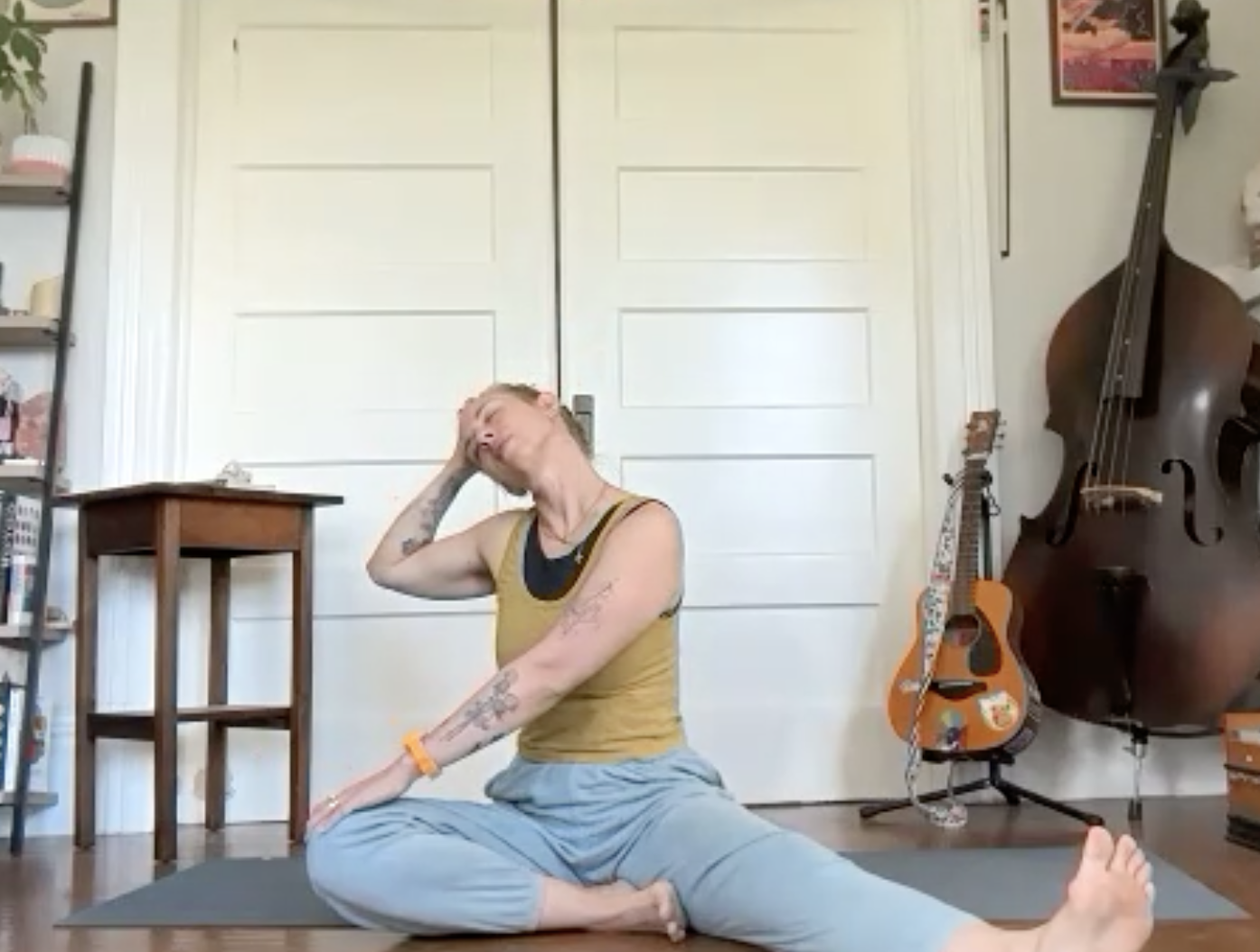 Person practicing yoga or stretching indoors, sitting on a yoga mat