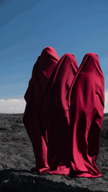 Cloak Trio. Three red-cloaked figures on lava rock, compositing, 2026
