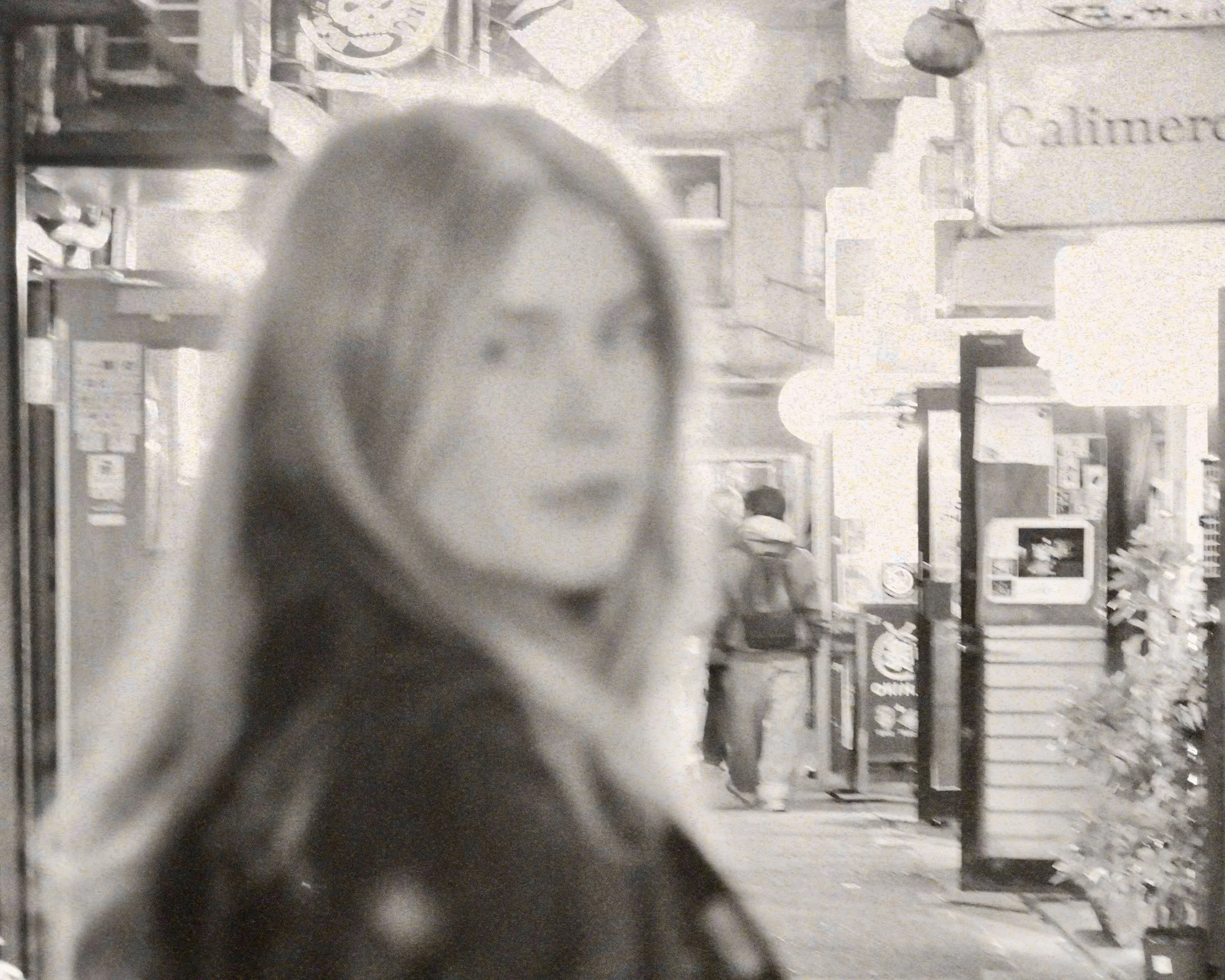 Person wearing an orange helmet and white tank top riding a zip line against a mountainous background with trees and rocky terrain.
