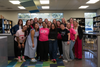 A group of Leveling the Fields Volunteers smiling and posing for a selfie inside a retail store, with athletic clothing racks and sports accessories in the background.