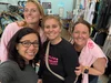 A group of Leveling the Fields Volunteers smiling and posing for a selfie inside a retail store, with athletic clothing racks and sports accessories in the background.