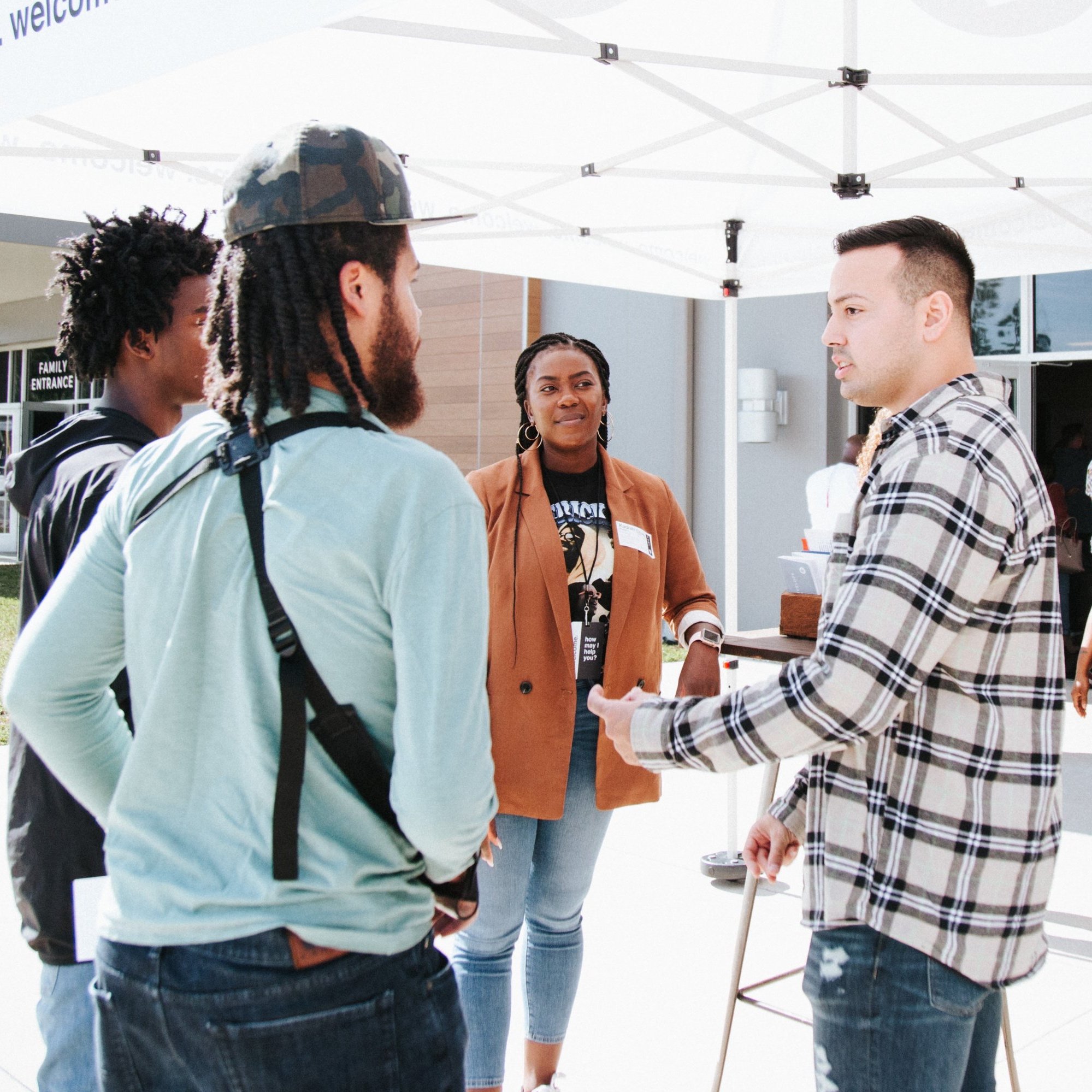  group of people talking under a tent outside of church 