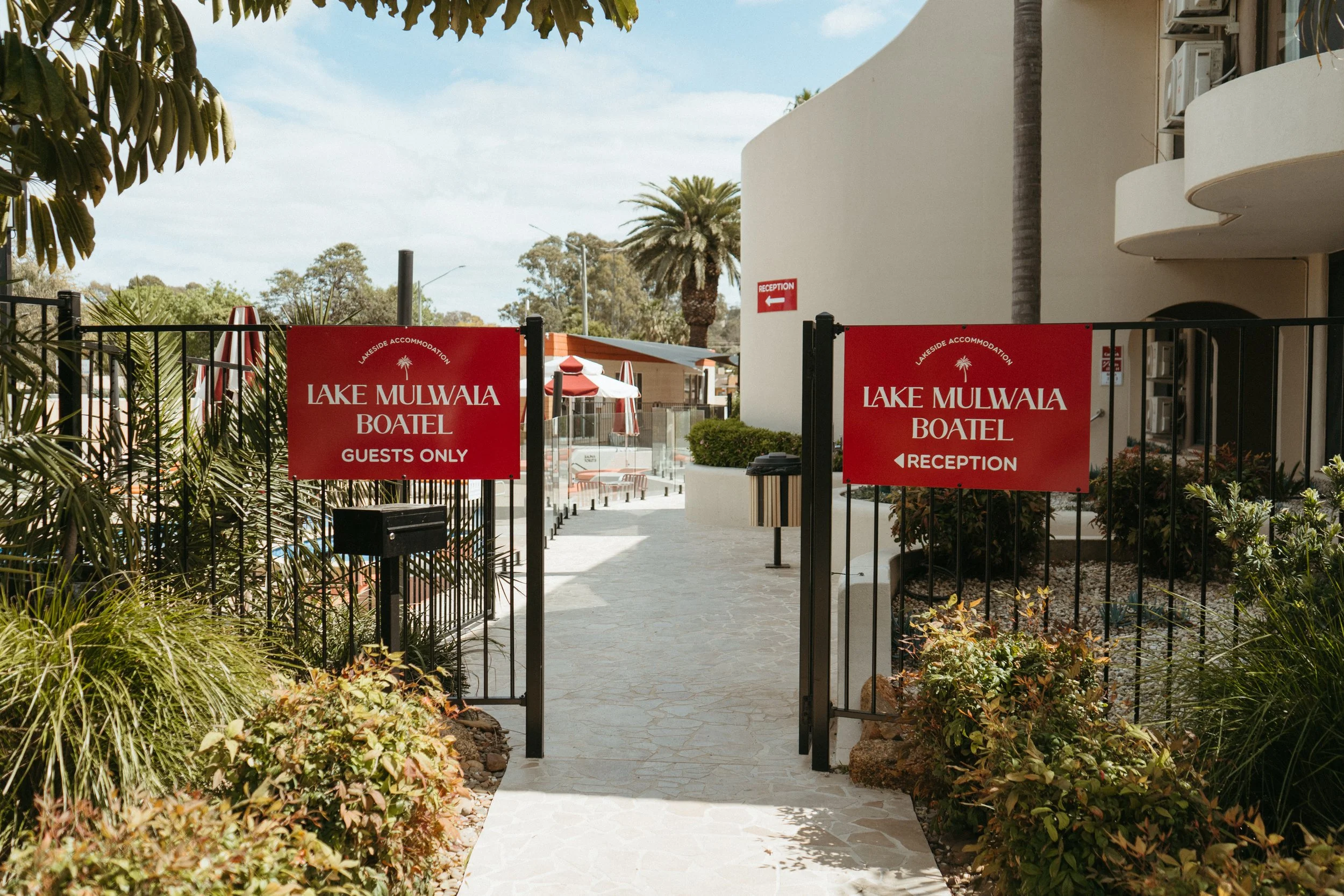 Lake Mulwala Yarrawonga - Entrance gate to Lake Mulwaia Boatel with signs indicating 'Guests Only' and 'Reception', surrounded by plants and outdoor seating visible in the background.