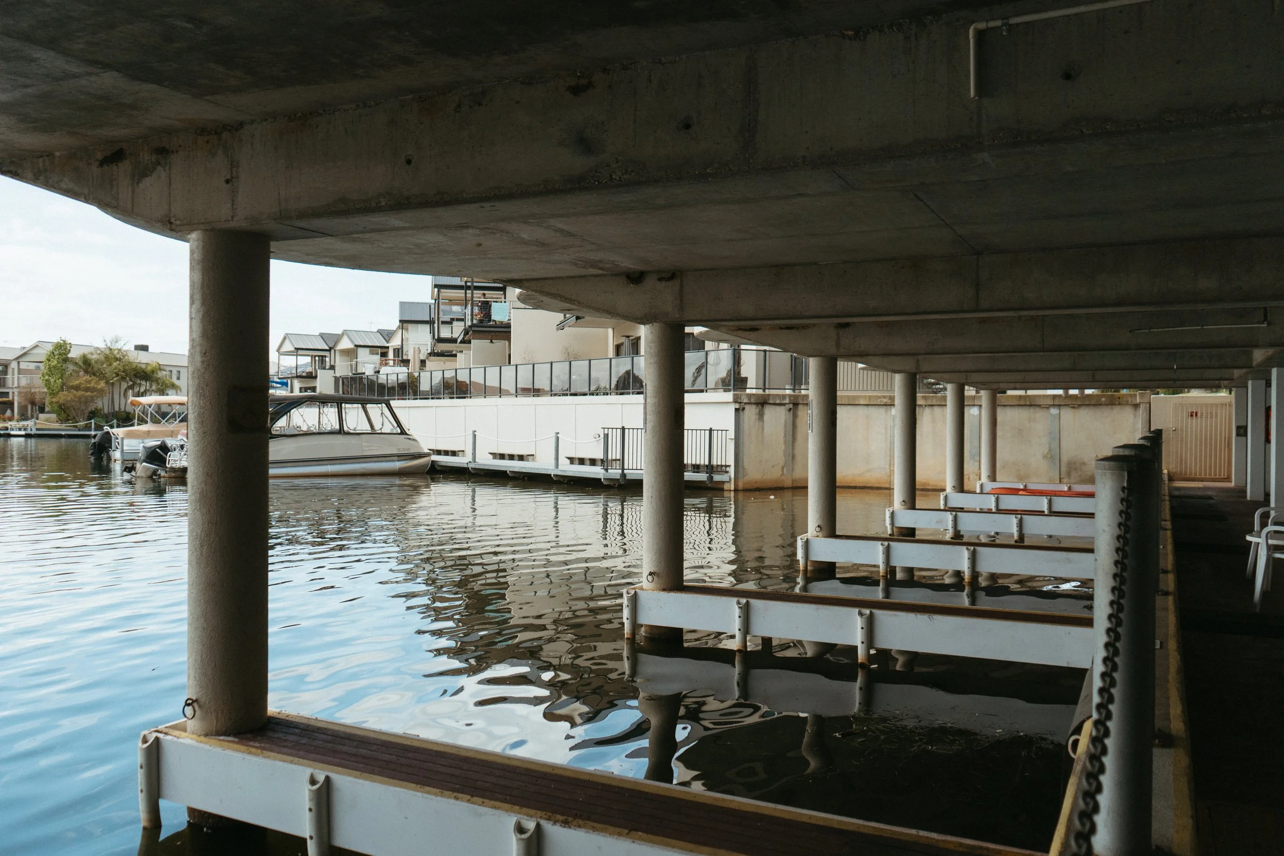 Lake Mulwala Yarrawonga - Underwater view of a marina with boats docked alongside concrete piers and houses in the background.