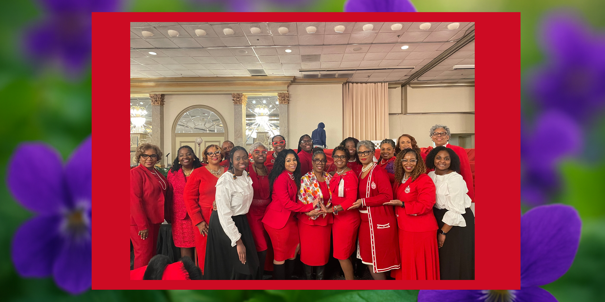 A group of women dressed in red and white formal attire posing together at an indoor event, smiling and standing close together.