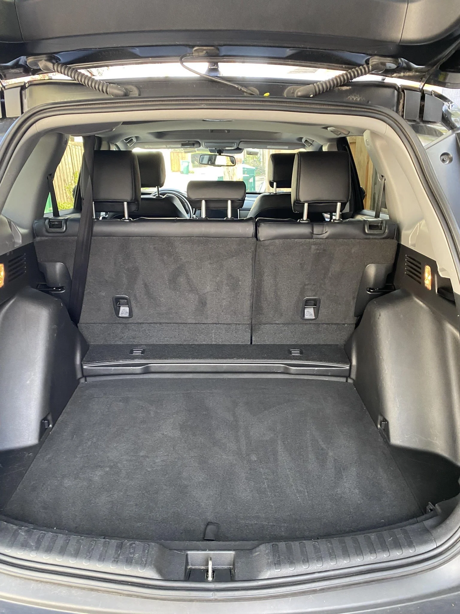 Open SUV trunk with folded back seats, showcasing ample cargo space, black interior, and rear seating visible.
