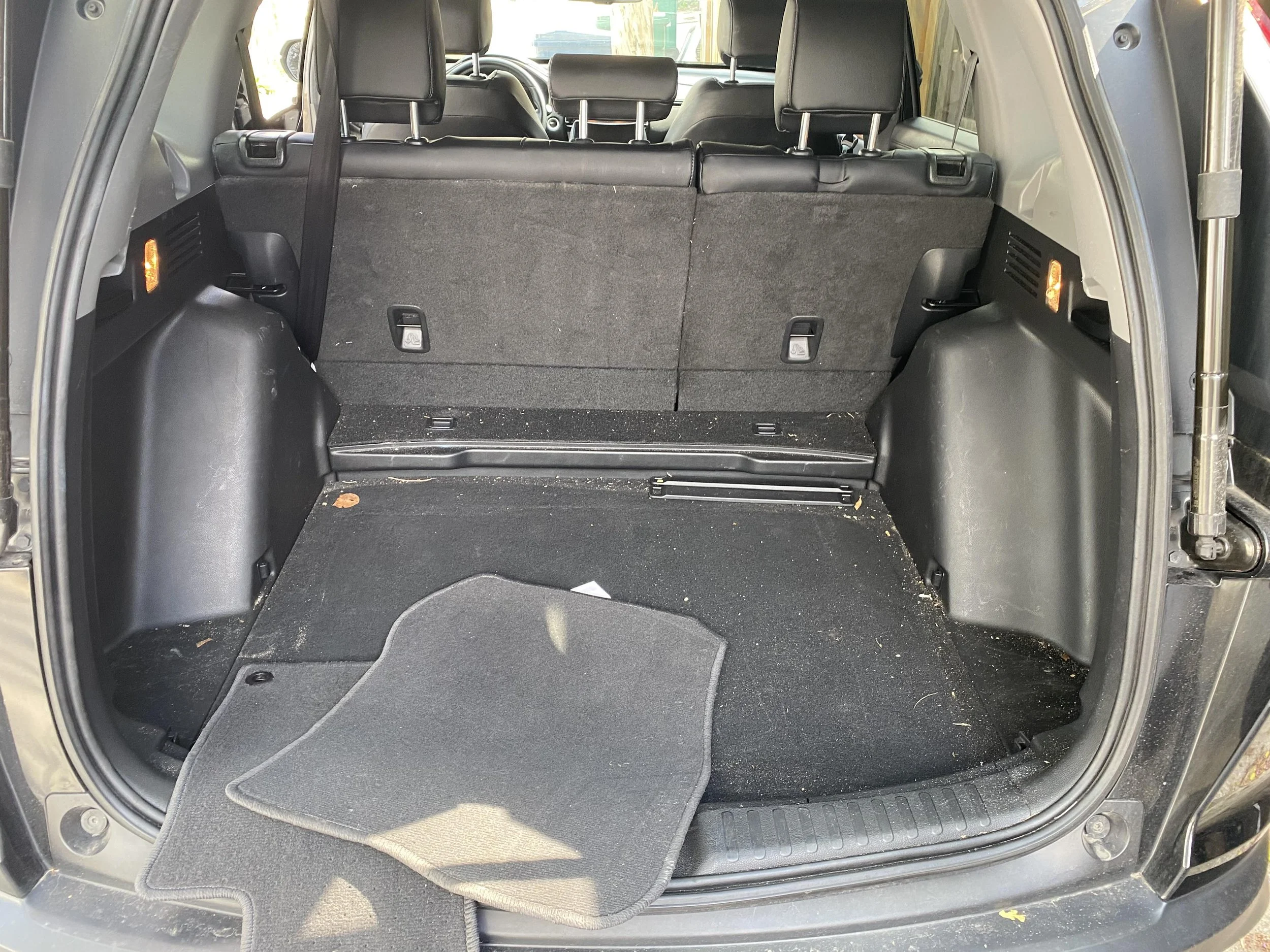 Open trunk of a vehicle with folded rear seats and floor mat