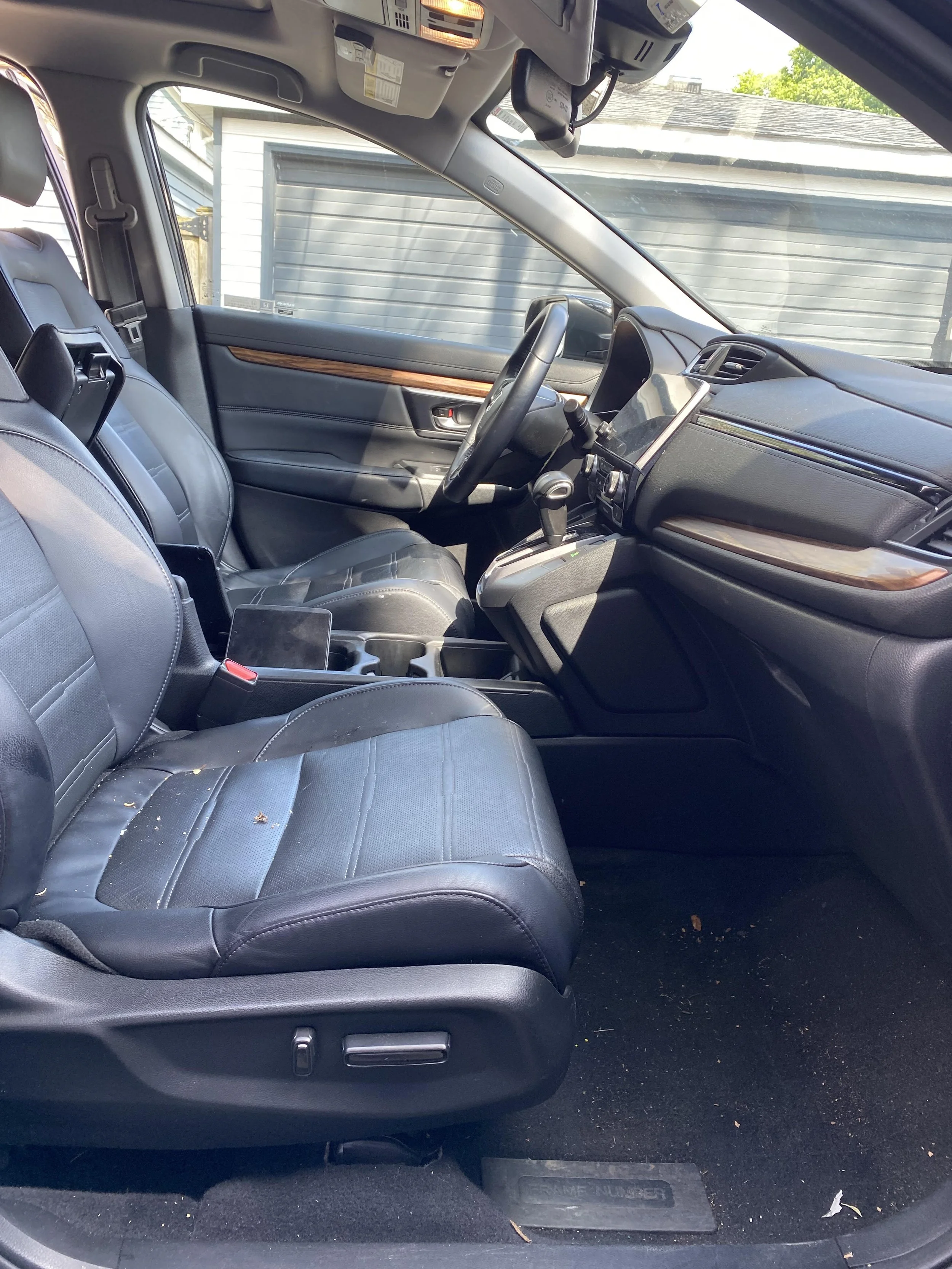 Interior of a car with black leather seats, a steering wheel, and a dashboard with a screen. Sunroof partially visible.