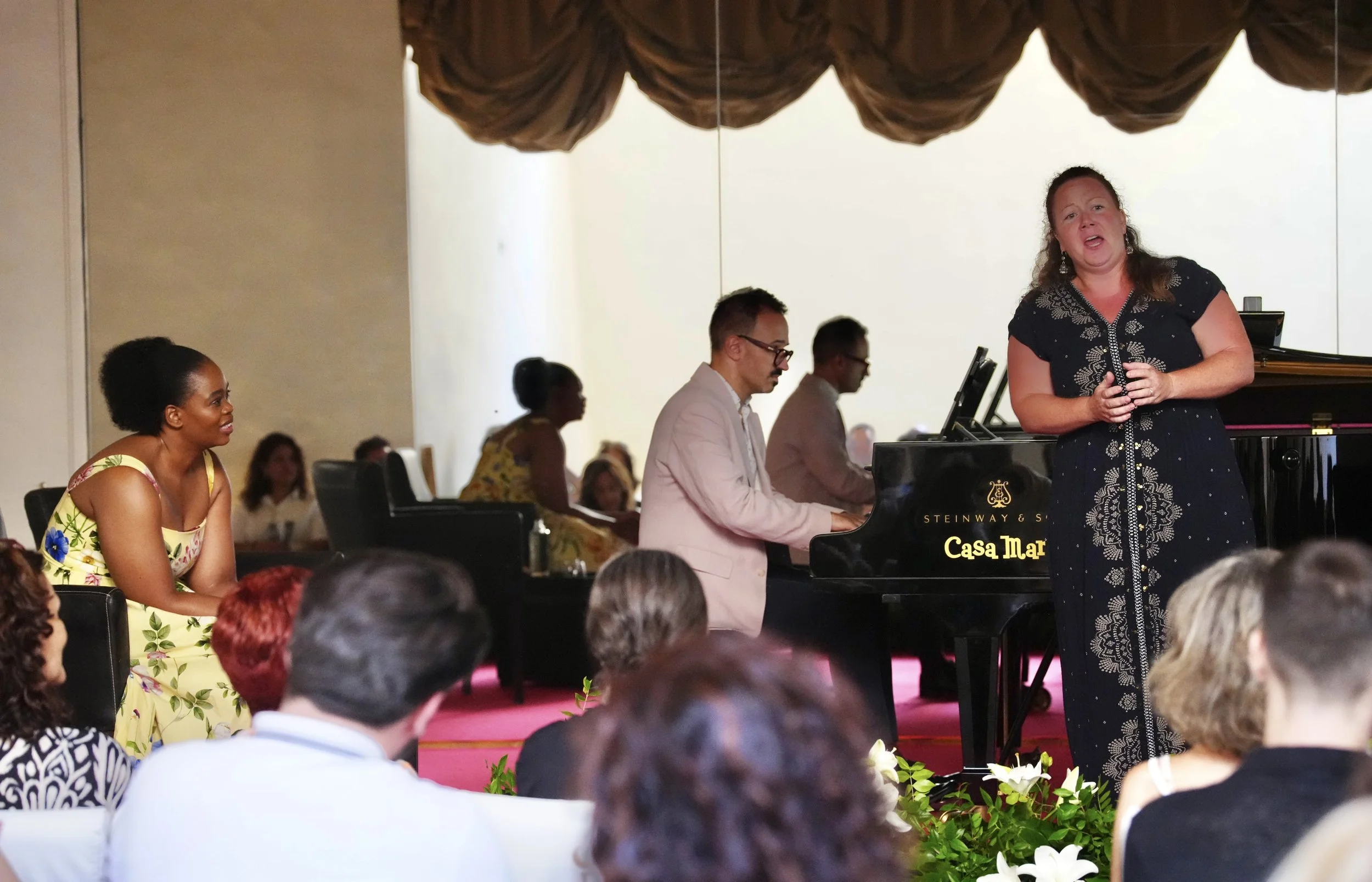 Una cantante y un pianista interpretando en un escenario en un concierto con audiencia.