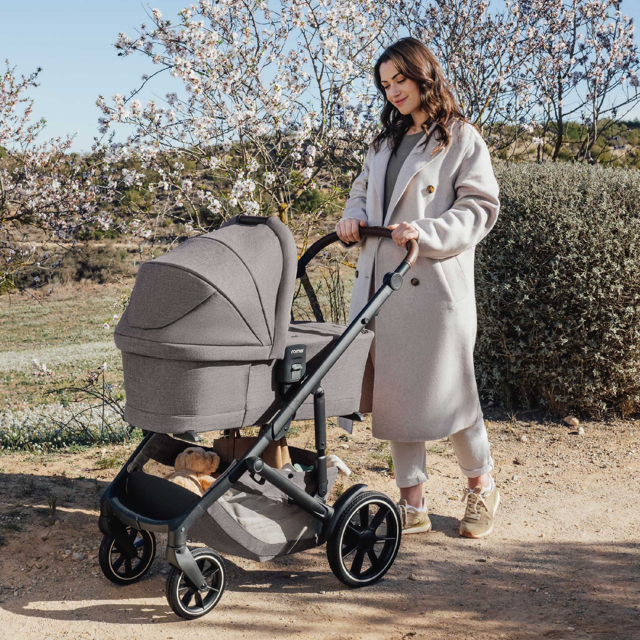 A woman pushing a bassinet stroller.