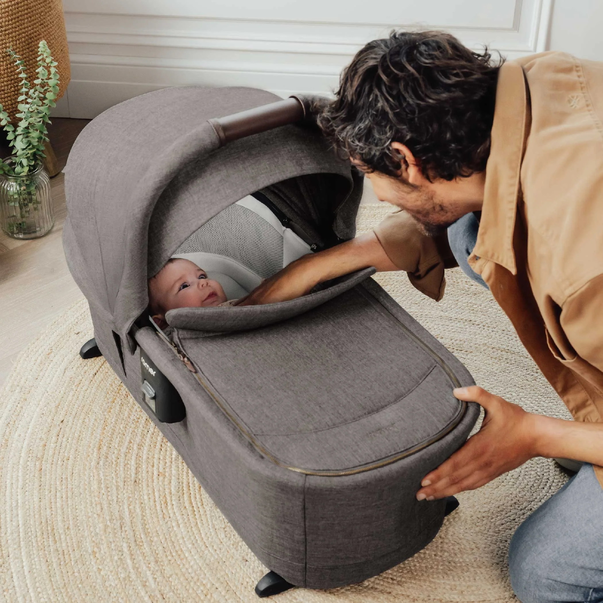 A man looking at a baby in a bassinet.