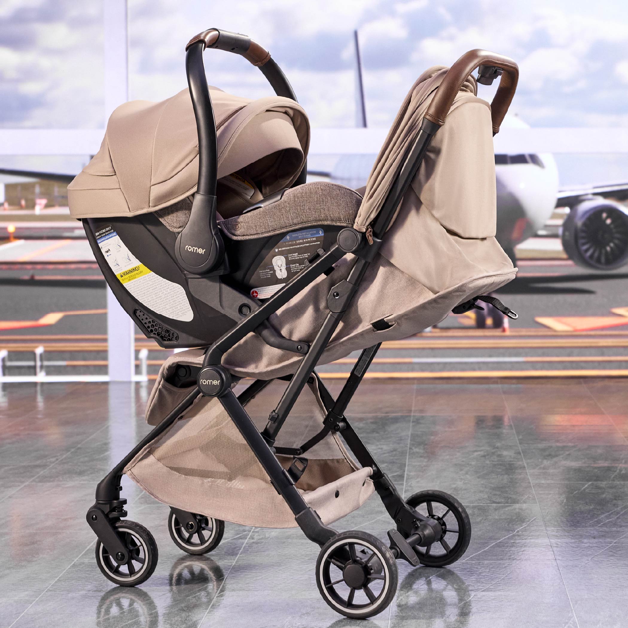 A tan baby stroller with a car seat attachment, with an airport runway and airplane visible in the background. (Copy)
