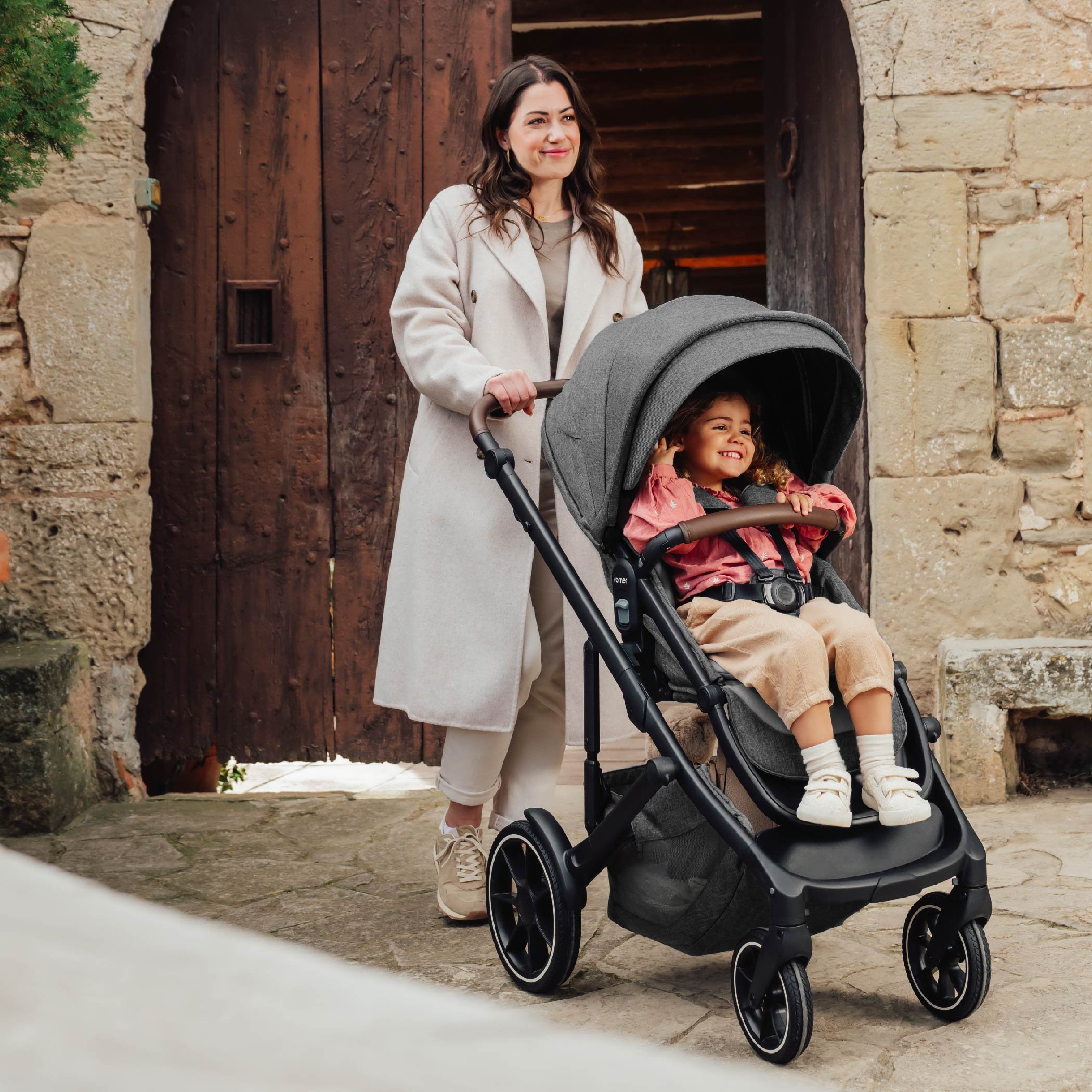 A woman pushing a toddler stroller.