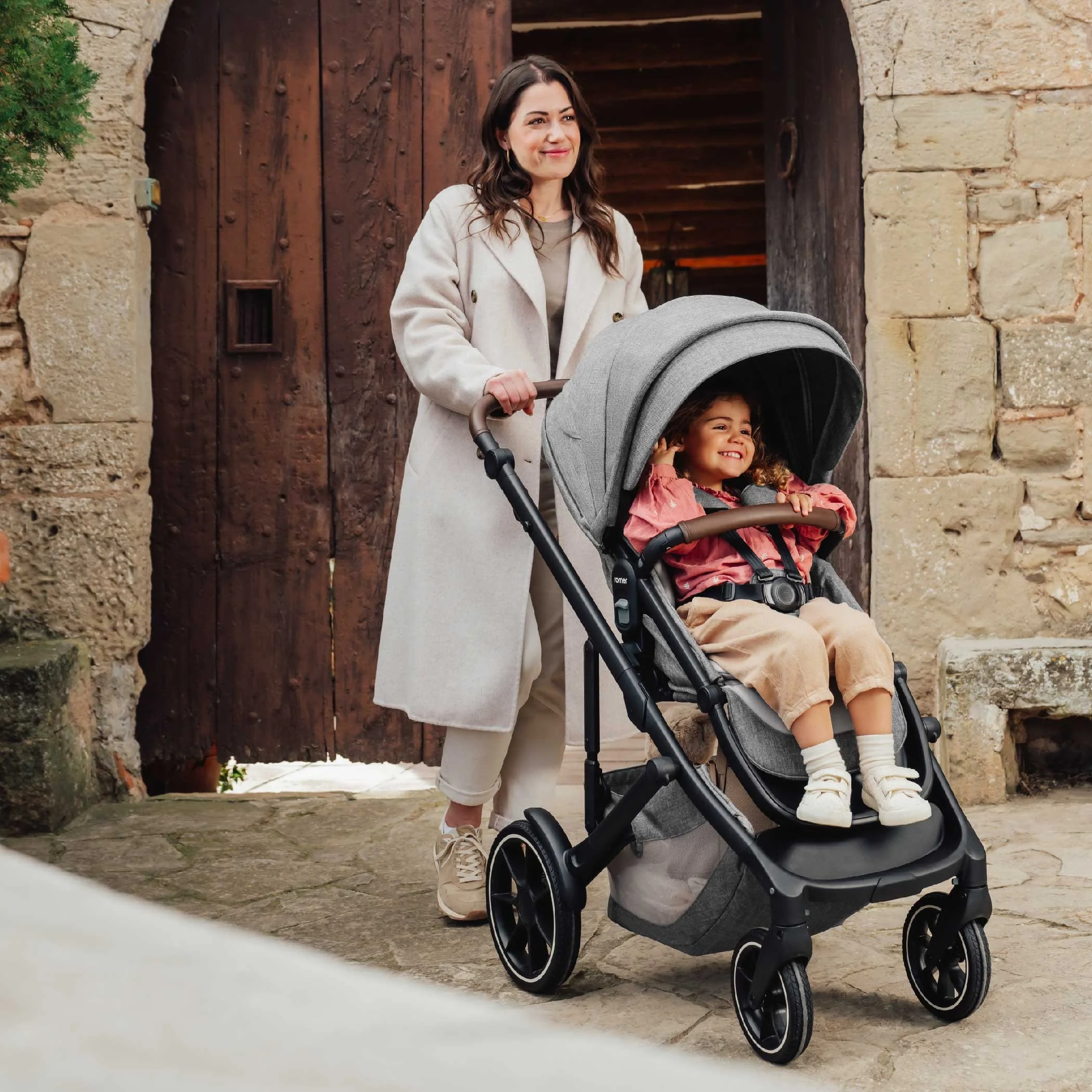 A woman pushing a toddler stroller.