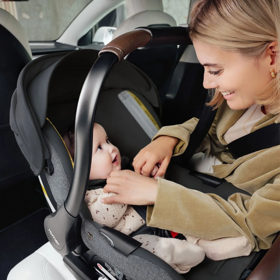 A woman looking at a baby in an infant car seat.