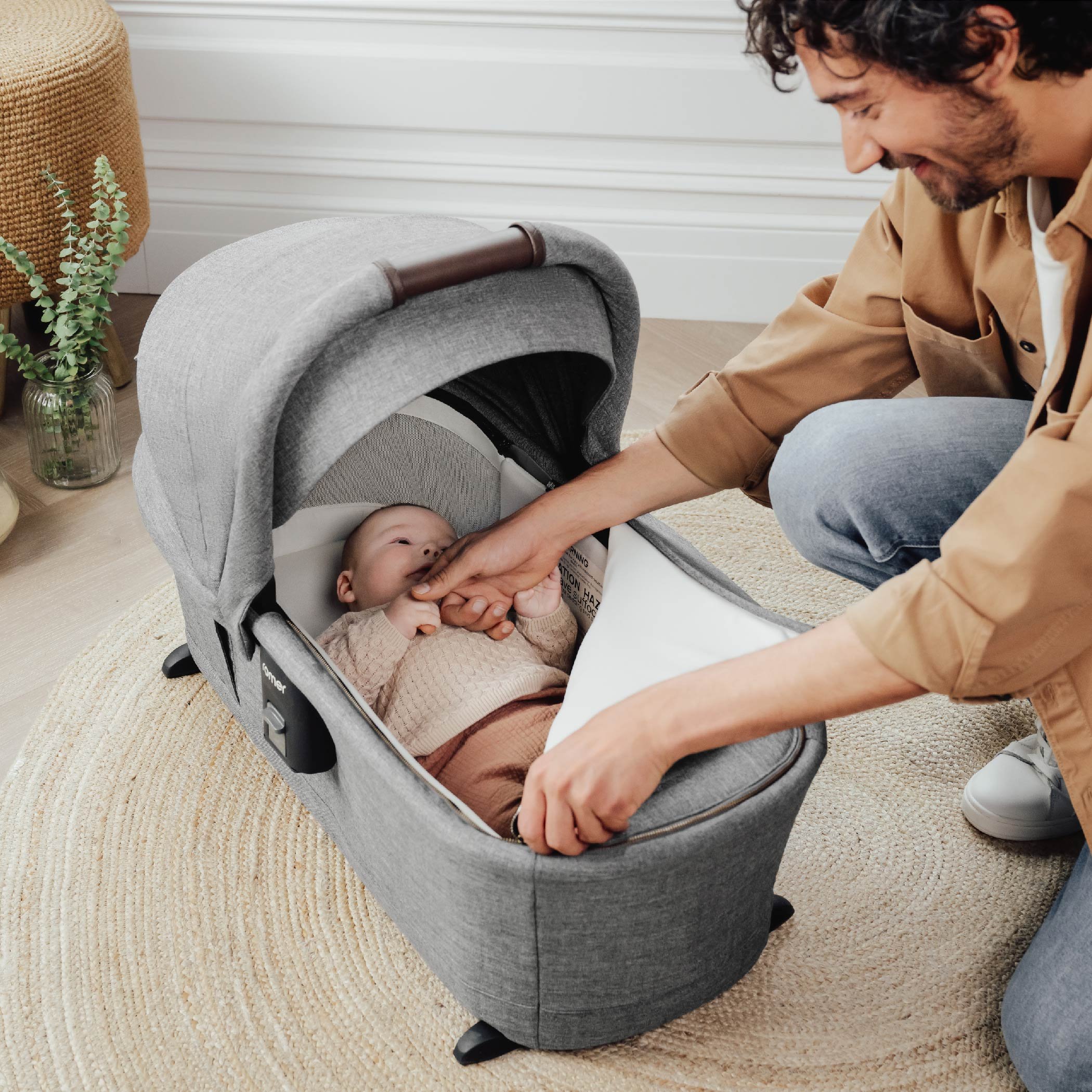 A man zipping up the foot cover on a baby bassinet