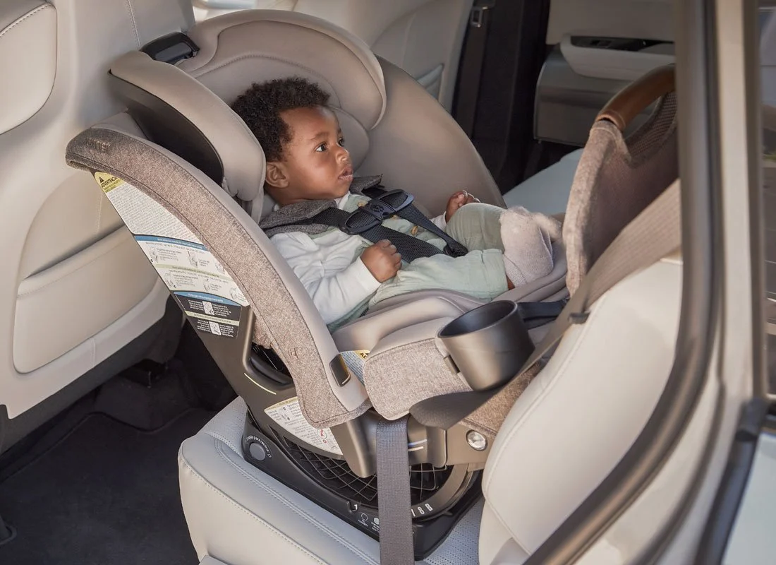 A baby secured in a rear-facing car seat in a vehicle. The car seat is installed with the vehicle seat belt.