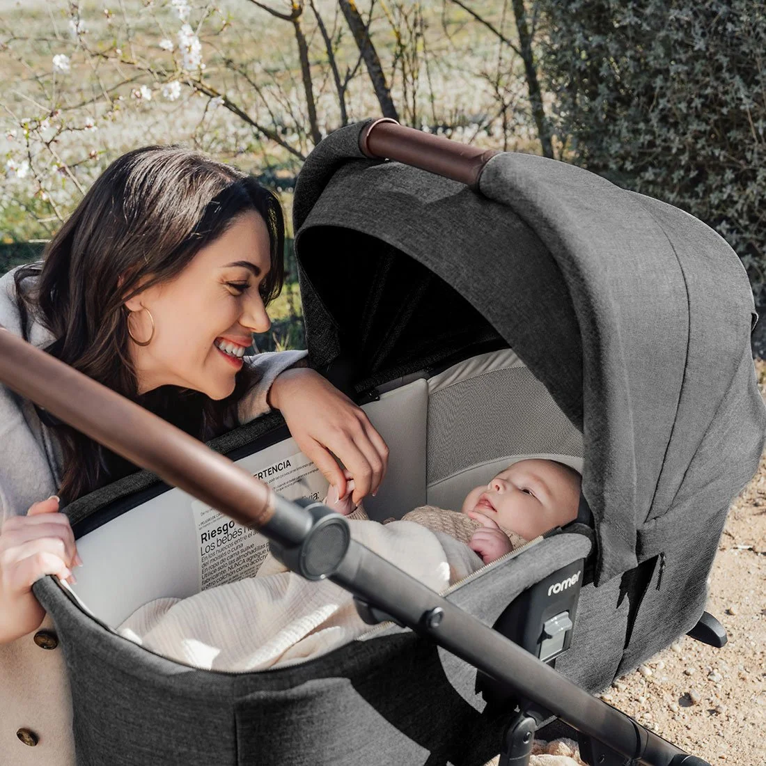 A woman looking at a baby in a bassinet stroller.