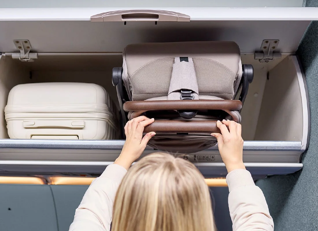 Woman placing stroller in the overhead compartment of an airplane.