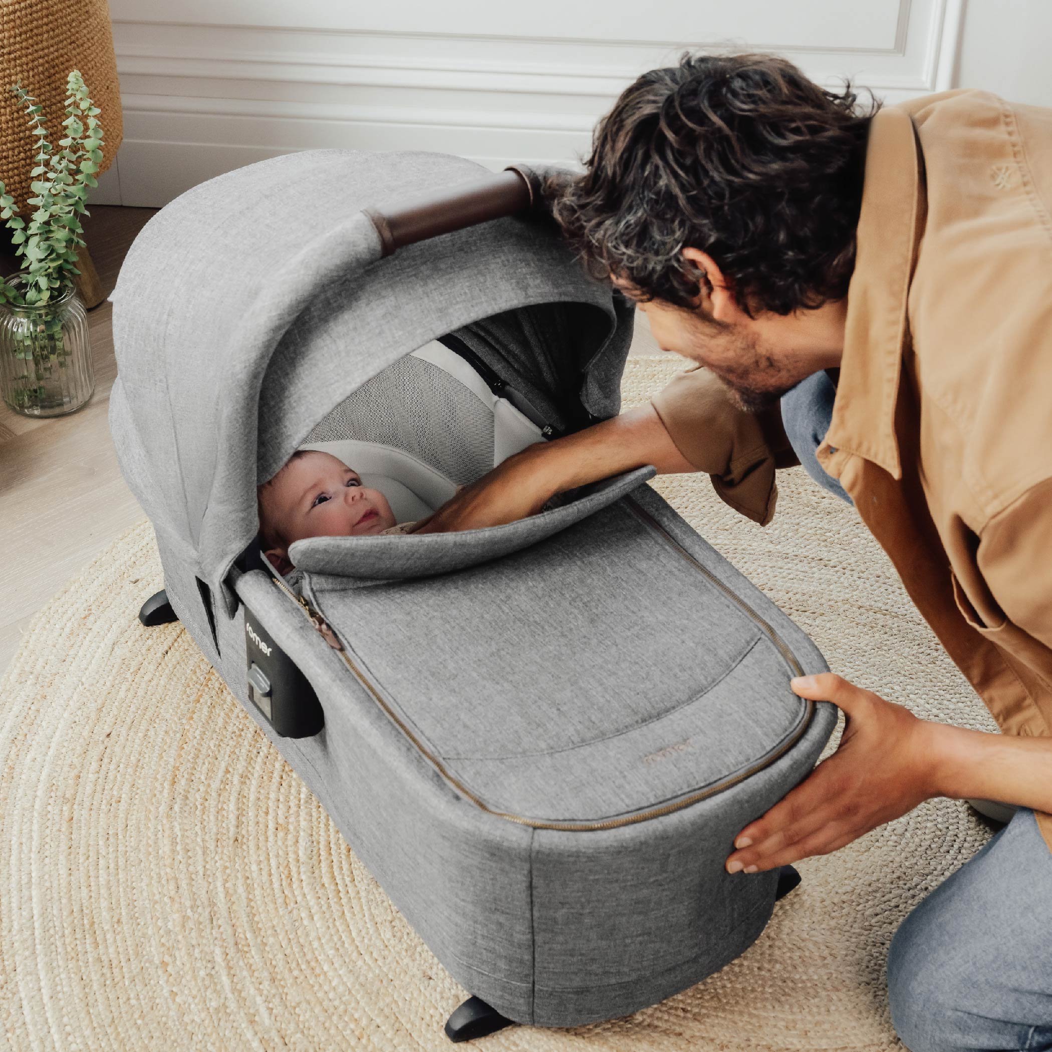 A man looking at a baby in a bassinet.