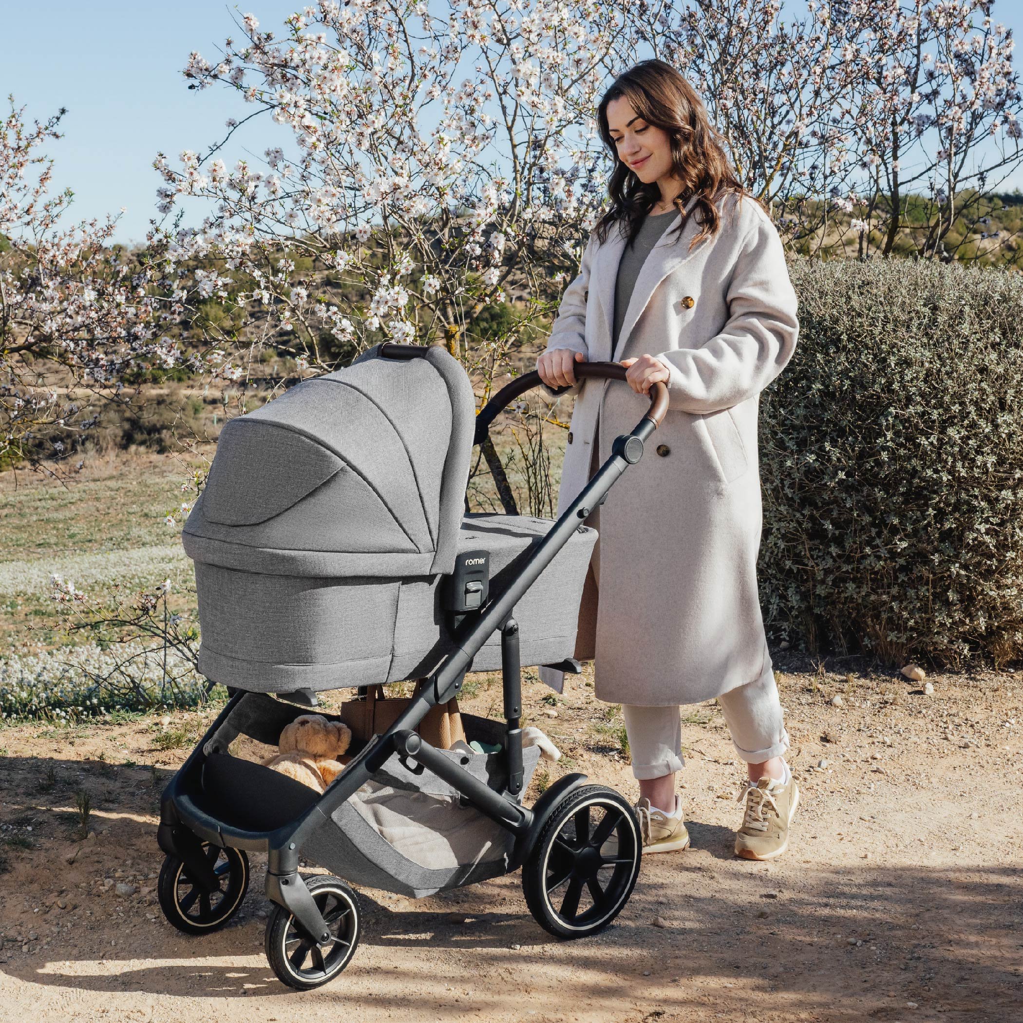 A woman pushing a bassinet stroller.