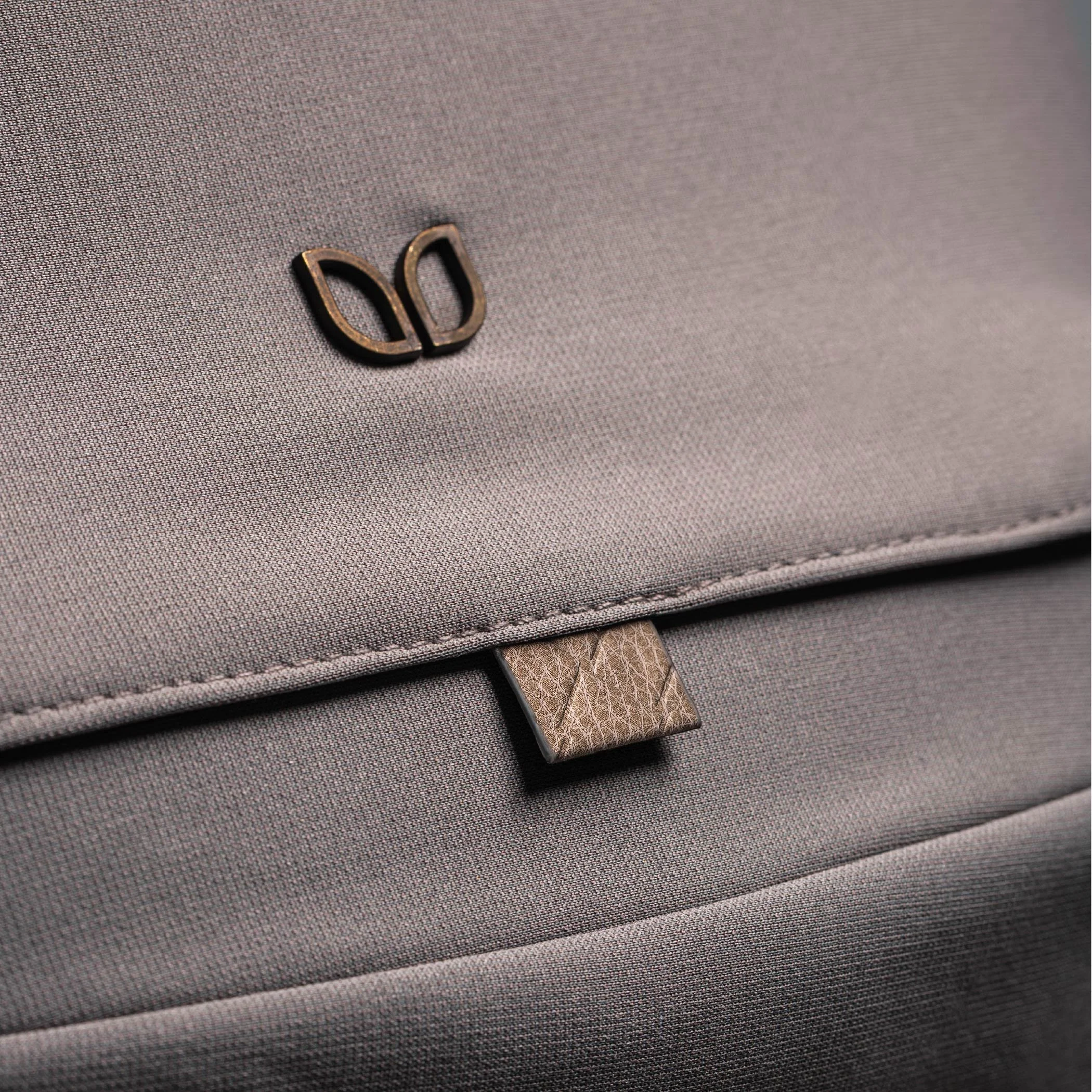 Textured fabric with leather accents and brown stitching.