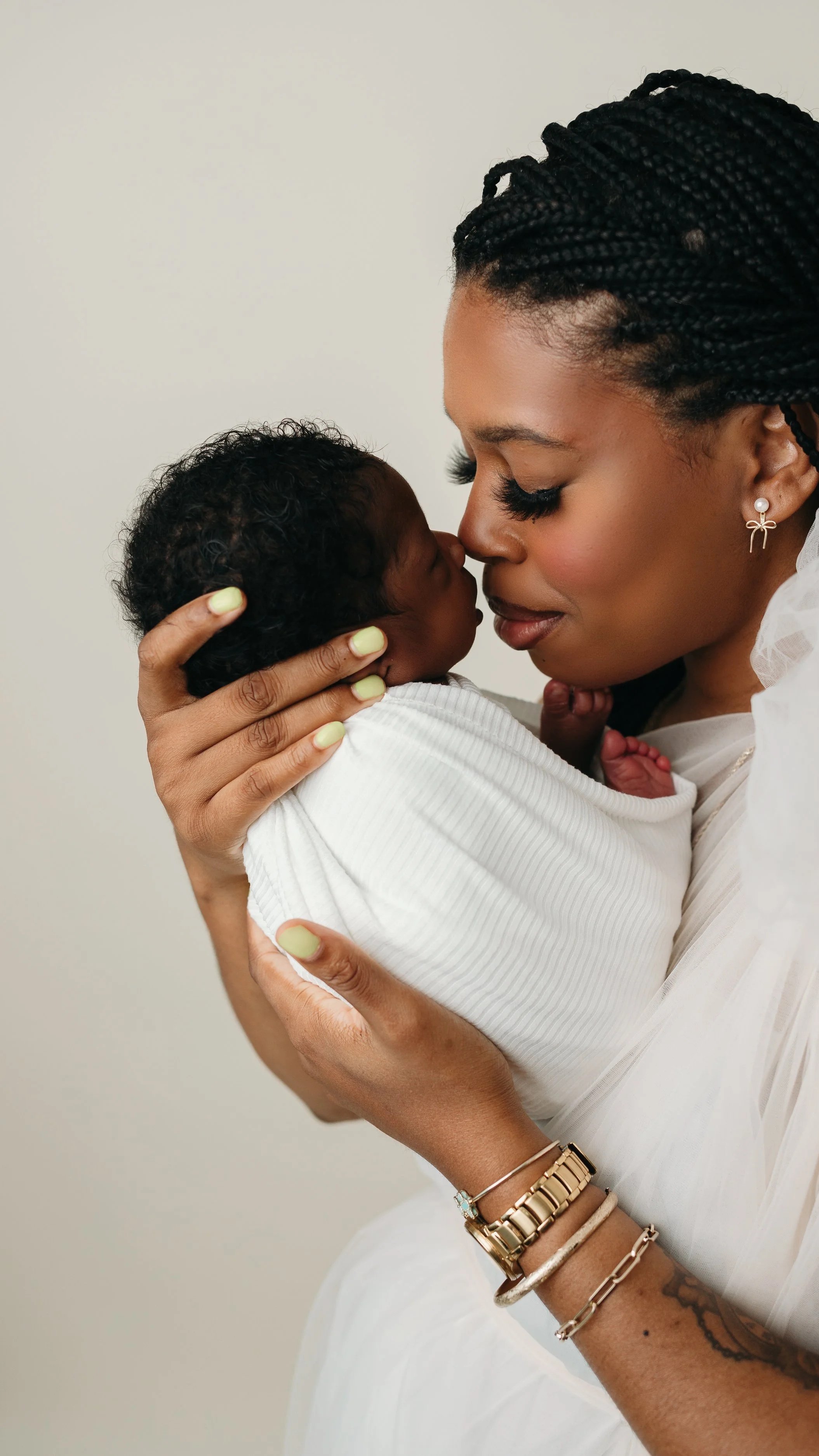 A mother holding her newborn baby close, touching foreheads in a tender moment.