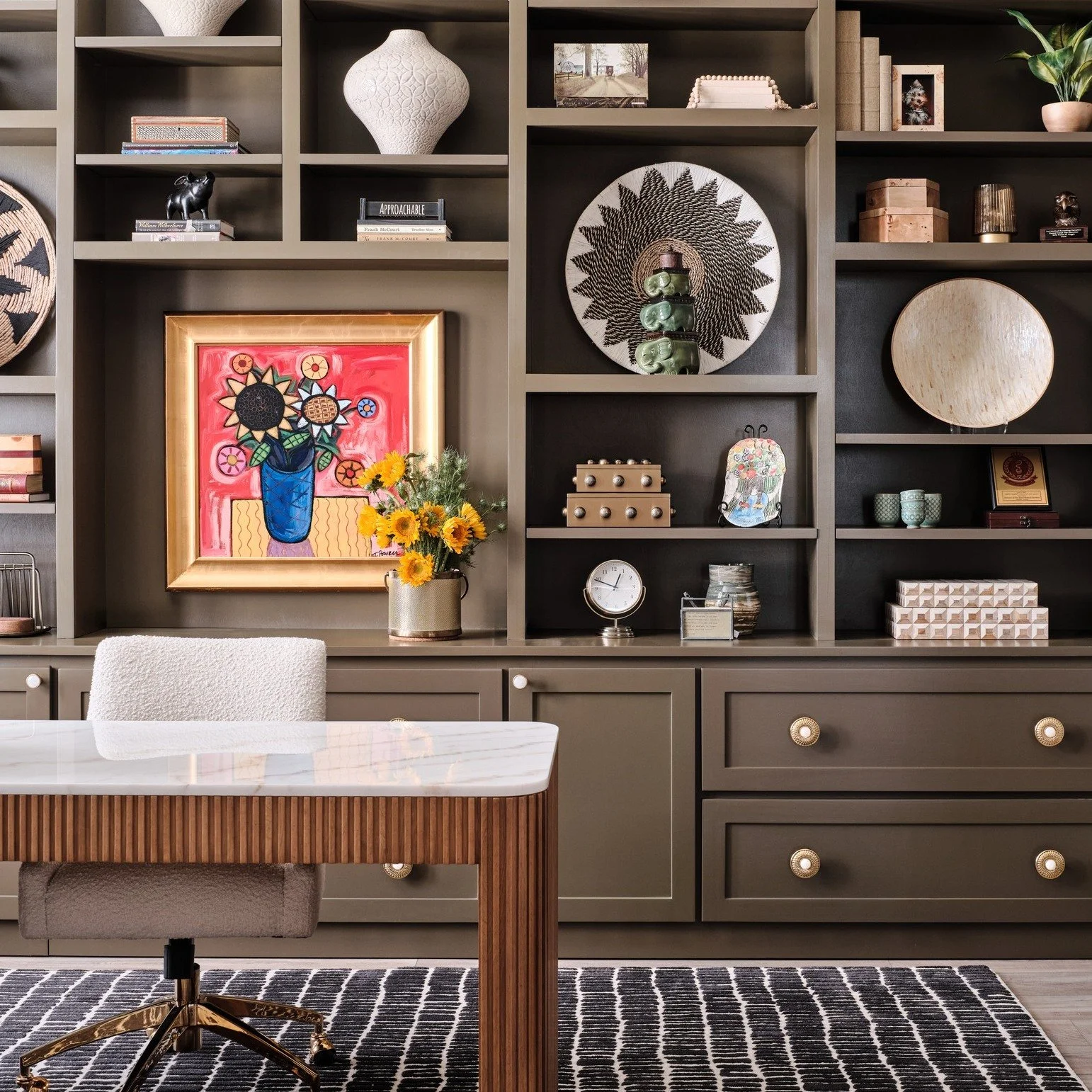This home office was designed to feel intentional, personal, and deeply livable.

We started with custom built ins in a moody green that ground the room and create a sense of calm focus. Rather than treating the shelves as purely functional, they bec