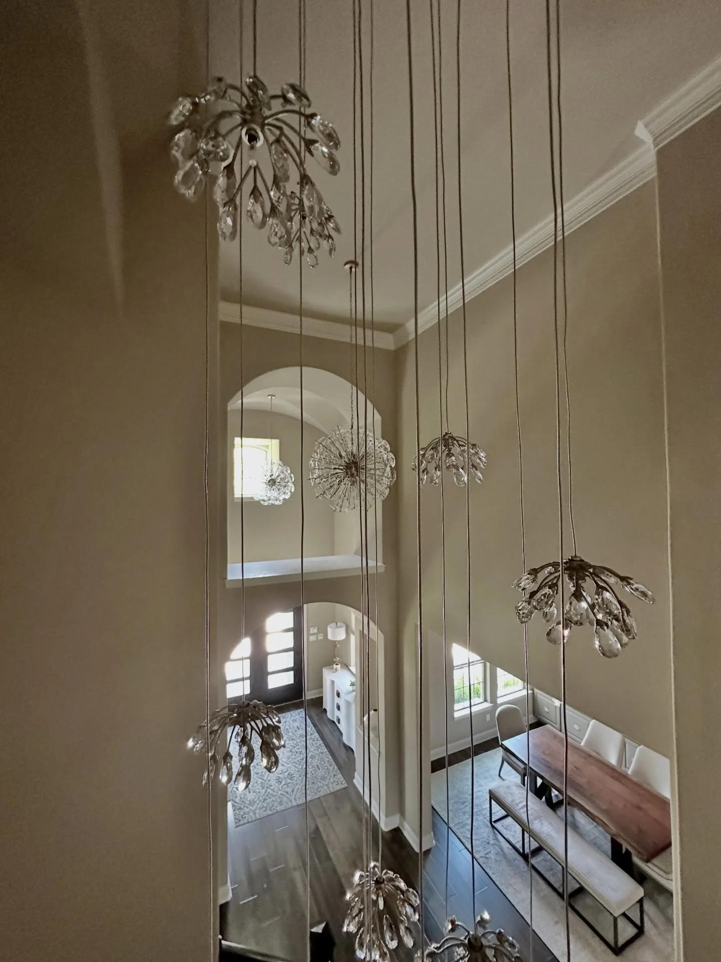 Lighting is not just functional. It shapes how a space feels.

In this entry, the cascading pendants draw your eye upward and define the vertical volume of the stair.

The sconces and two poppy chandeliers in the foyer create a secondary moment, conn