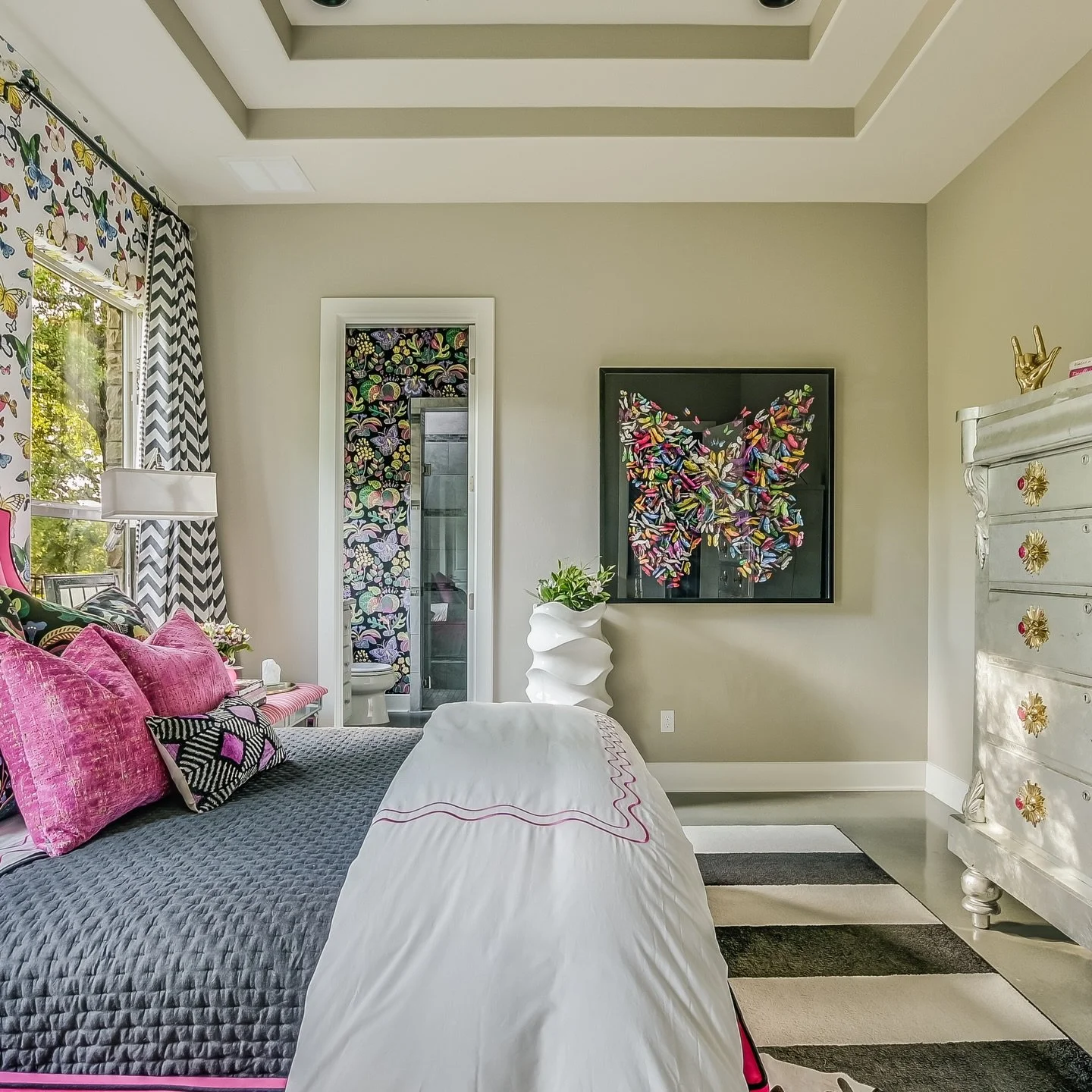 This space was designed to feel bold, joyful, and completely personal. From the velvet fuchsia bed to the layered pattern, oversized vintage chest, and playful mix of art and color, every detail was chosen to give the room its own unmistakable person
