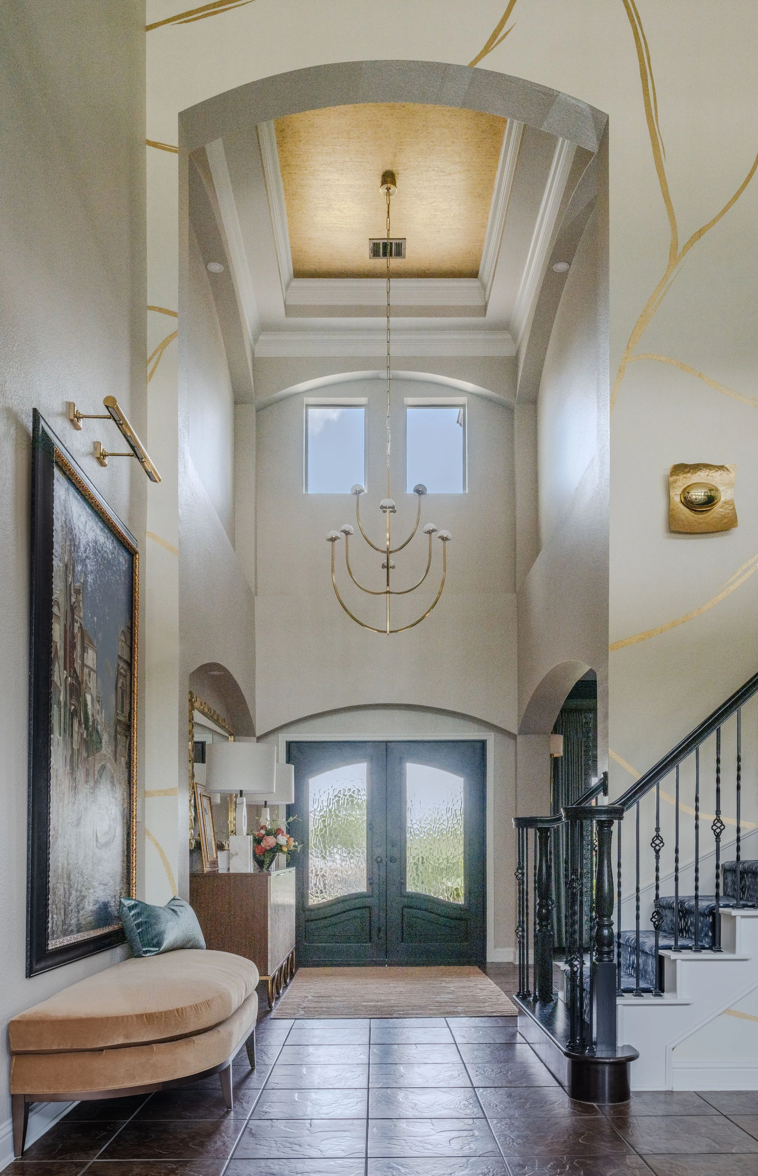 This grand foyer at the Schug Cove project was designed by Cyndi Hopkins Design to create an unforgettable arrival experience through scale, artistry, and layered detail. The luxury Austin Texas entry features a soaring ceiling, sculptural chandelier