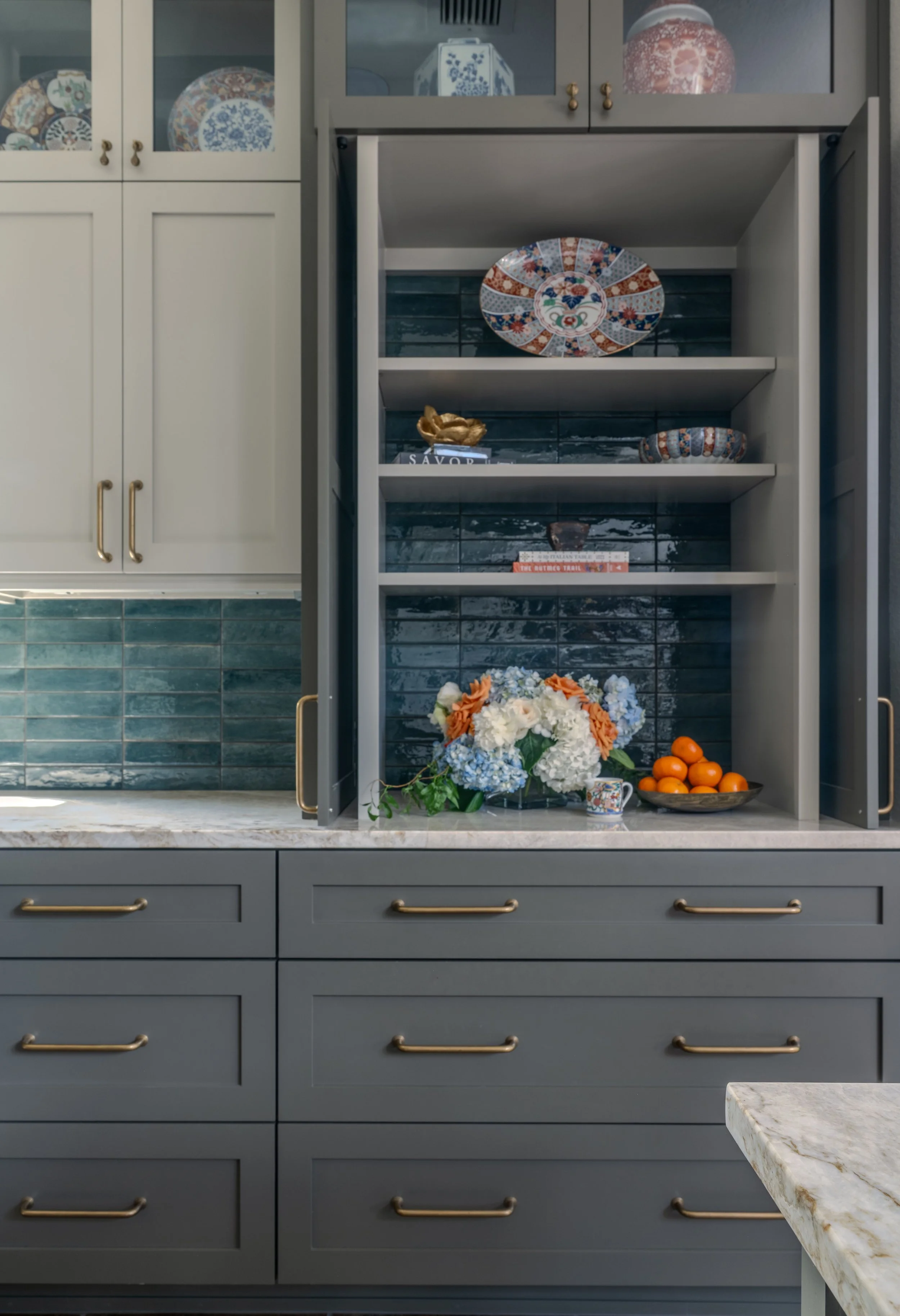 This kitchen at the Gabriel Woods project combines custom cabinetry, layered storage, and a rich blue tile backsplash to create a functional yet highly personalized space. Cyndi Hopkins Design balanced clean architectural lines with warm finishes, br