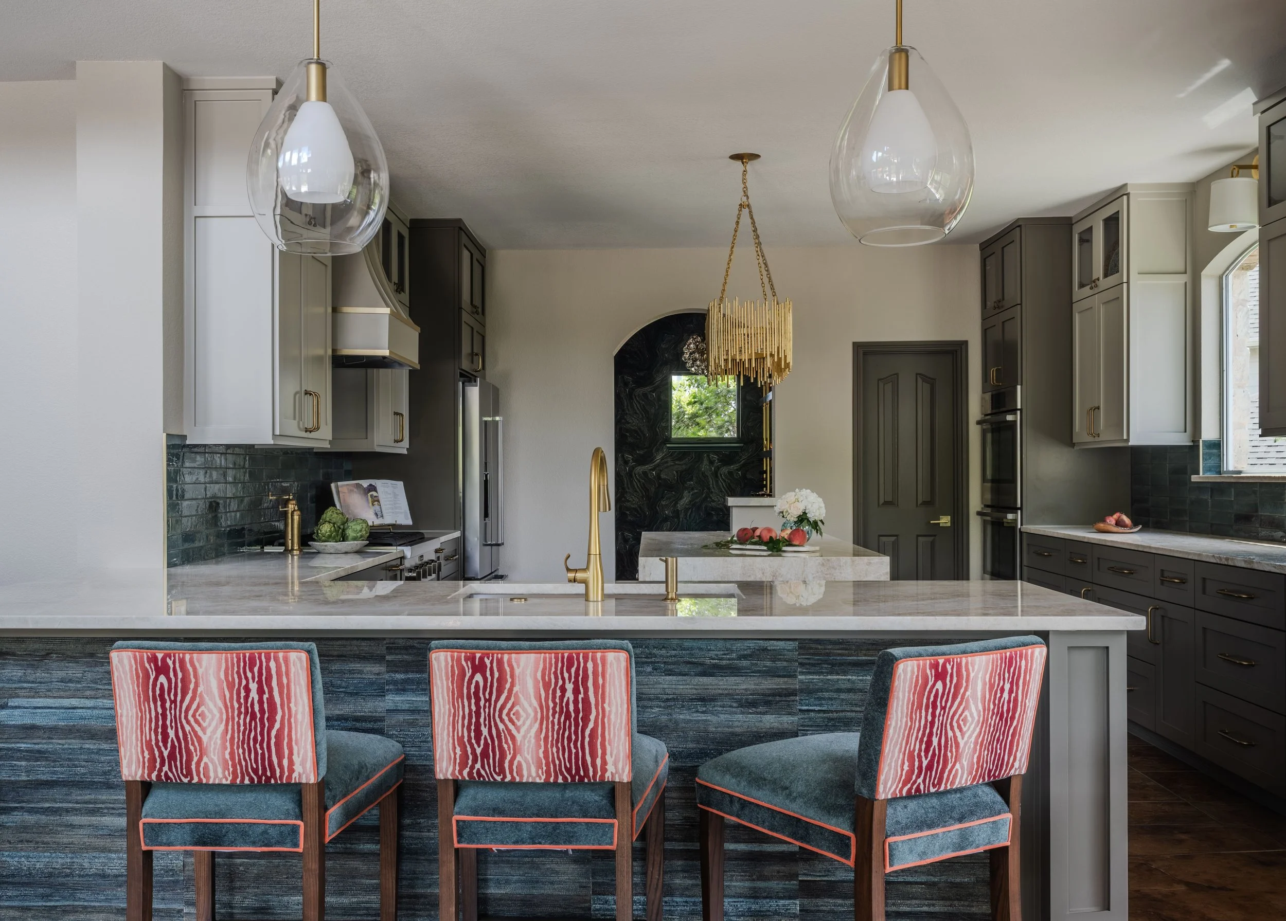 This luxury kitchen at the Schug Cove project combines quartzite countertops, custom cabinetry, handcrafted tile, and tailored barstools to create a sophisticated yet welcoming gathering space. Cyndi Hopkins Design layered rich texture, sculptural li