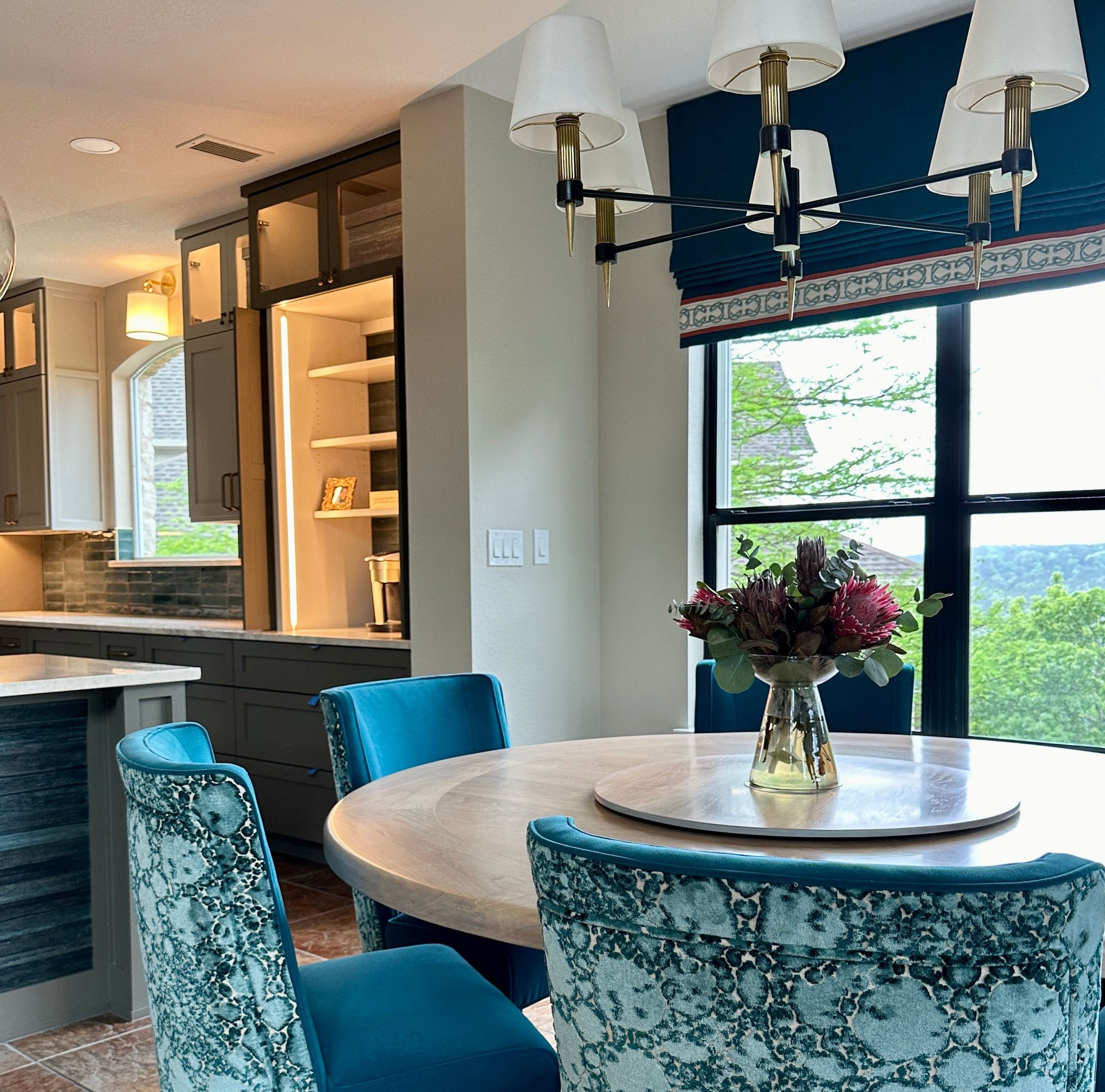 This breakfast room at the Gabriel Woods project was designed to feel both vibrant and welcoming, with layered blue tones, custom seating, and tailored window treatments creating a cohesive connection to the surrounding living spaces. Cyndi Hopkins D